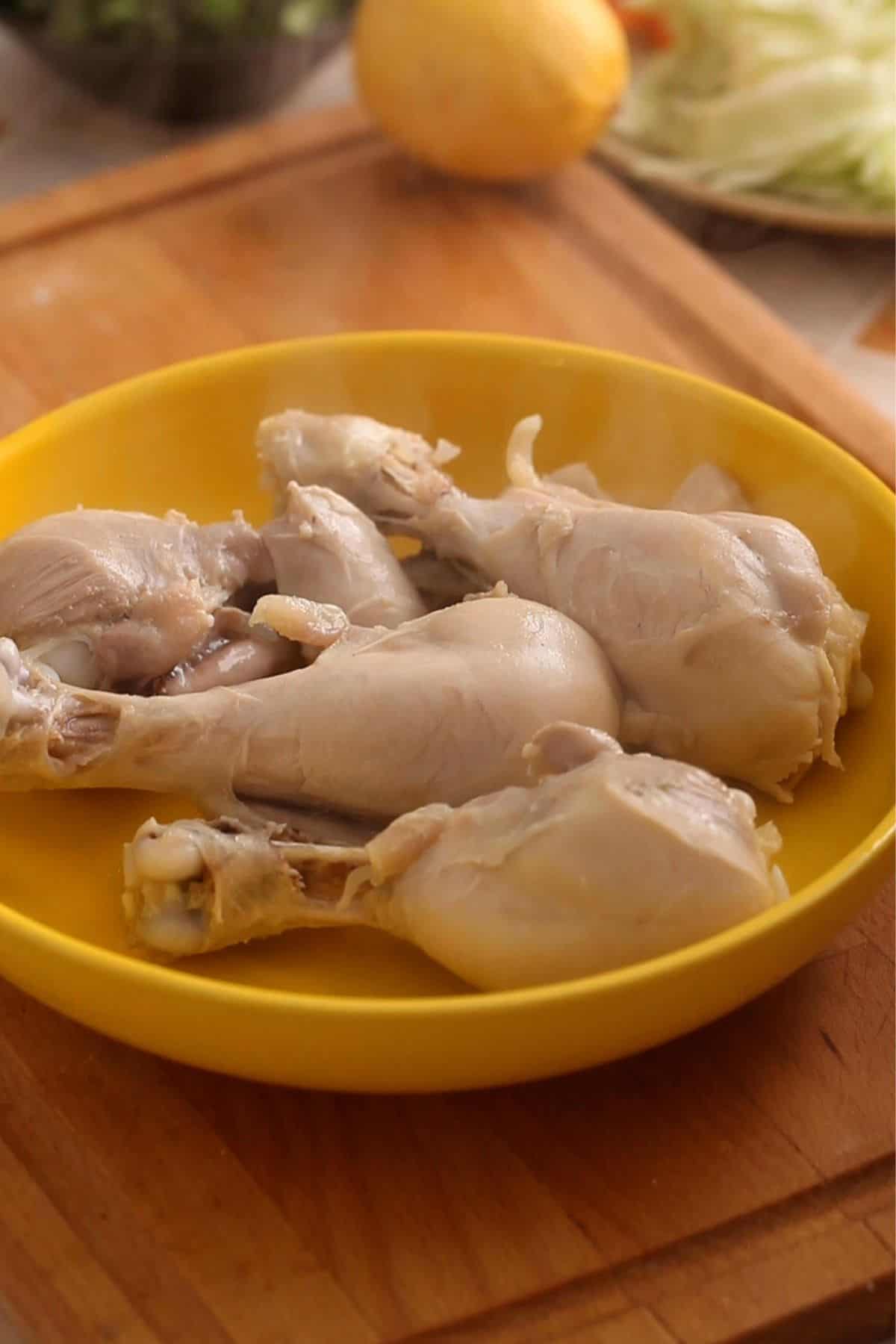 Cooked chicken drumsticks are placed on a yellow plate.