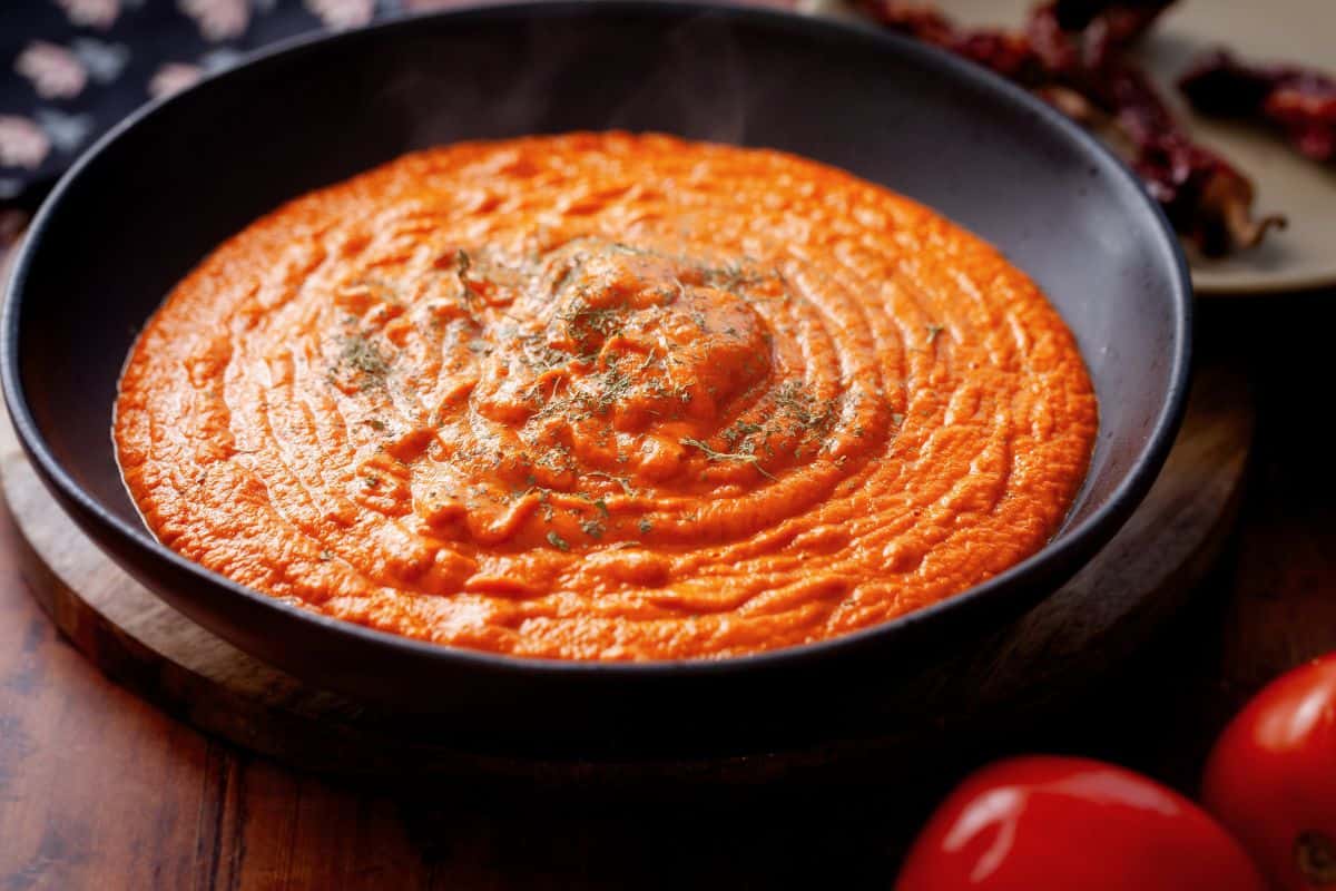 Side image of Butter chicken sauce in a large black bowl.