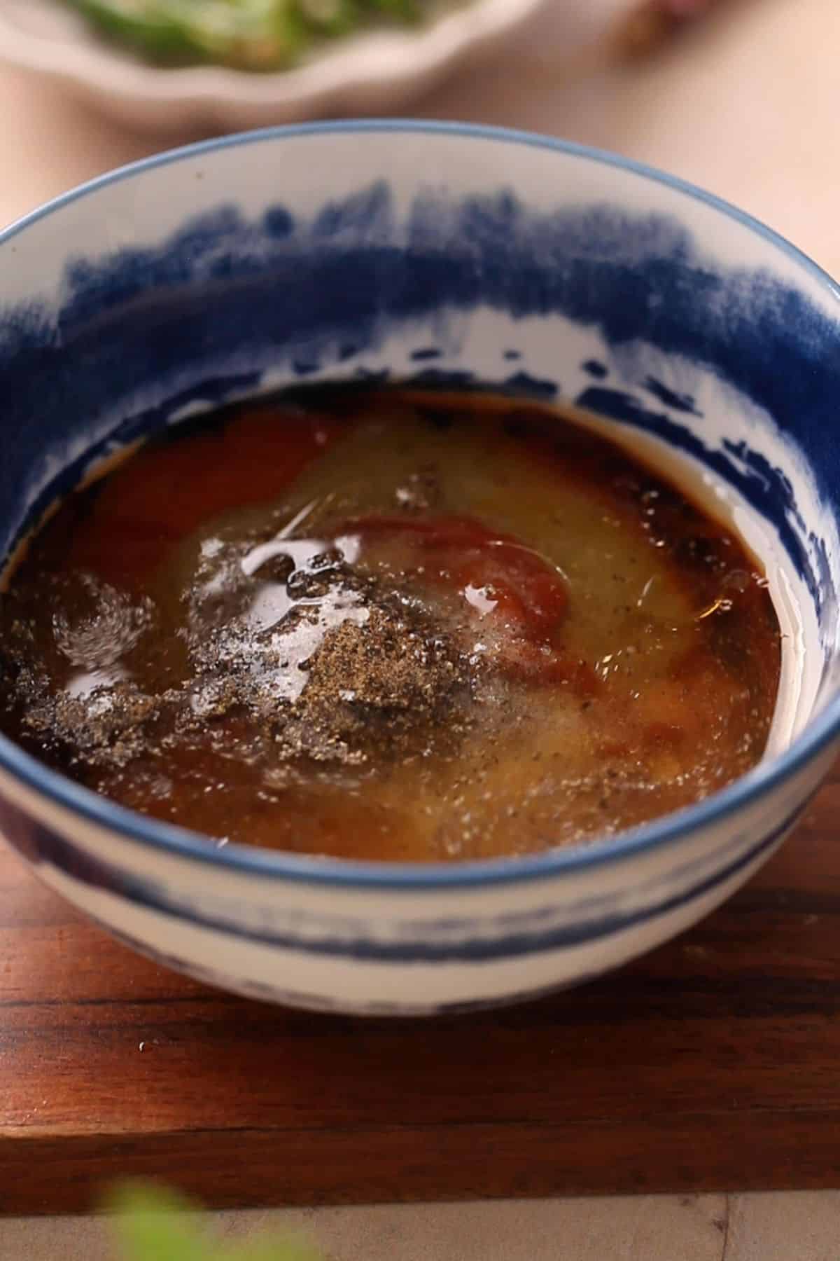 Stir fry sauce ingredients are added to a blue and white bowl.
