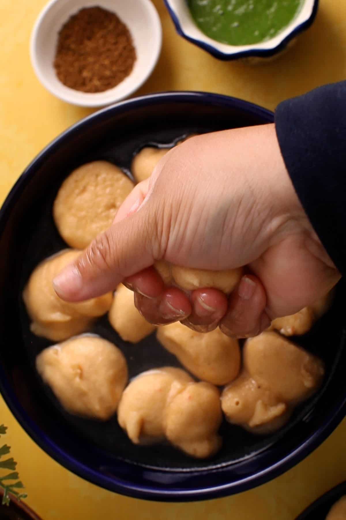 Excess water is squeezed from bhalla after soaking.