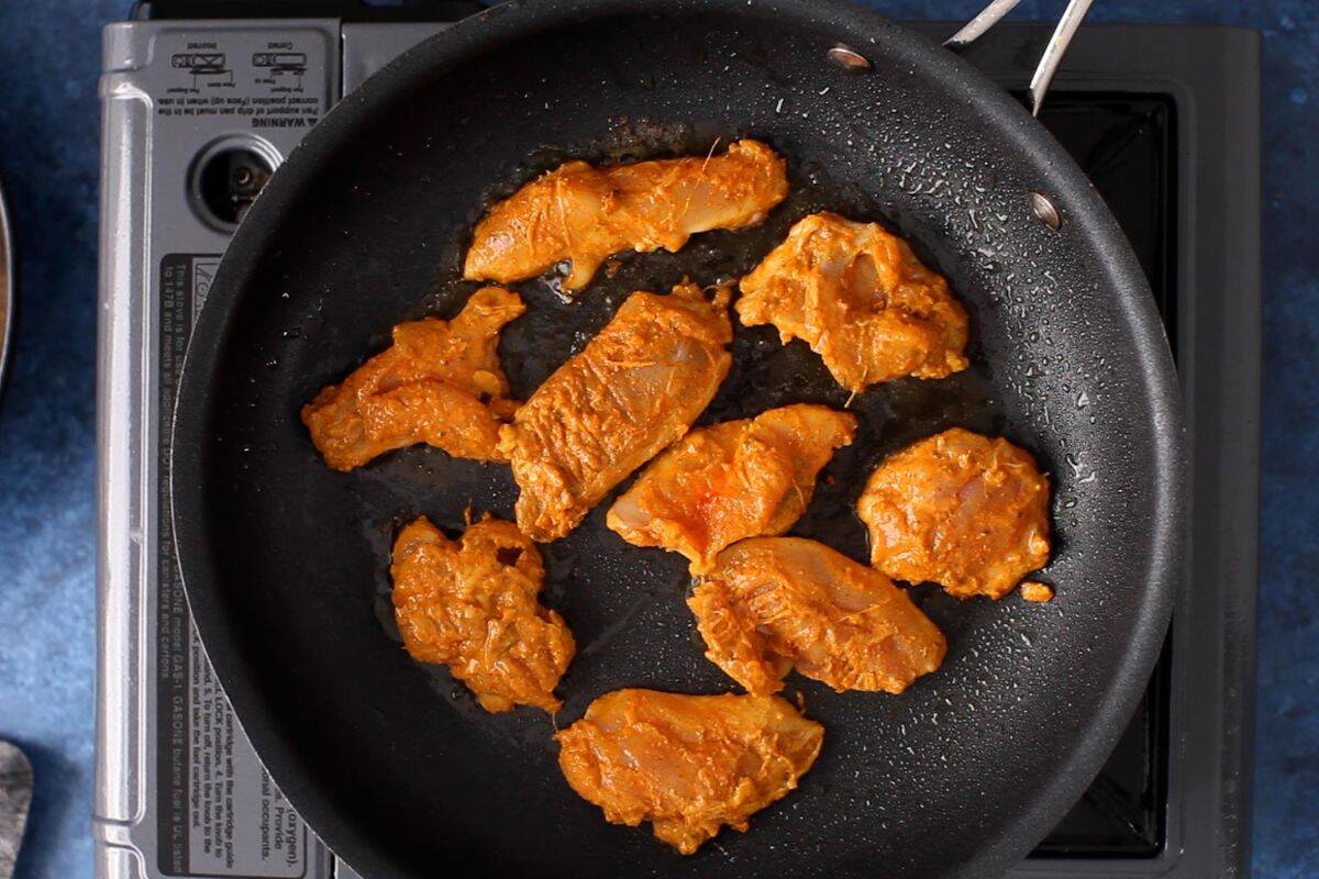 Marinated chicken is placed on a hot skillet.
