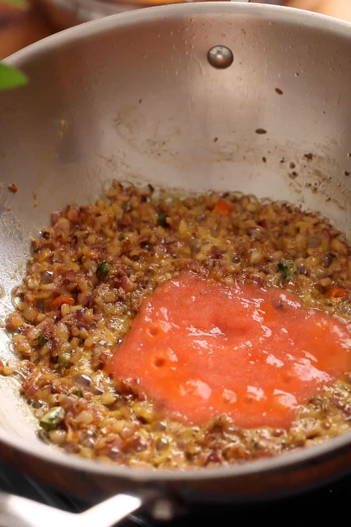 Crushed tomato is added to the onions.
