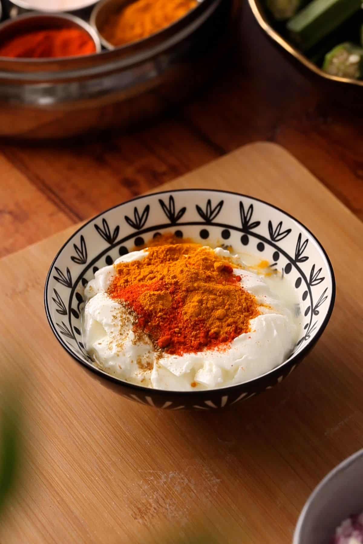 A black and white patterned bowl filled with yogurt topped with colorful spices.