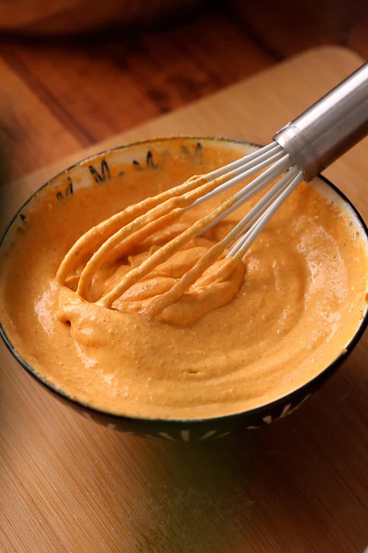 Yogurt is whisked to smooth using a small, metal whisk.