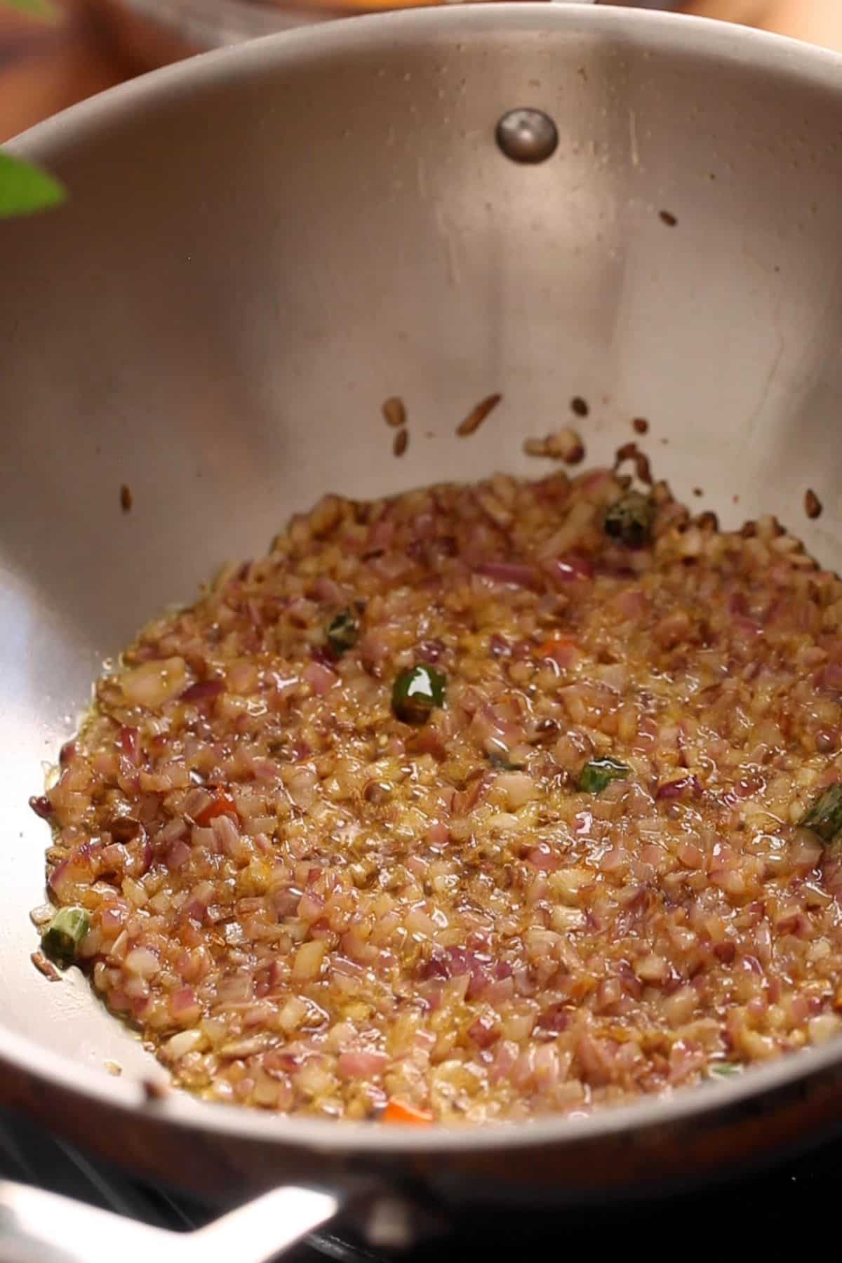 Browned onions in a stainless steel indian wok.