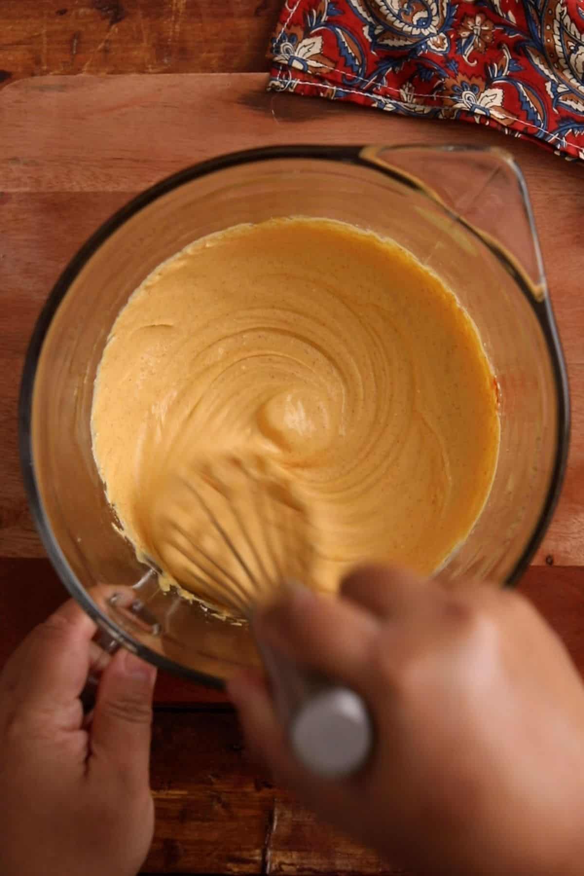 Yogurt and besan are whisked using a metal whisk.