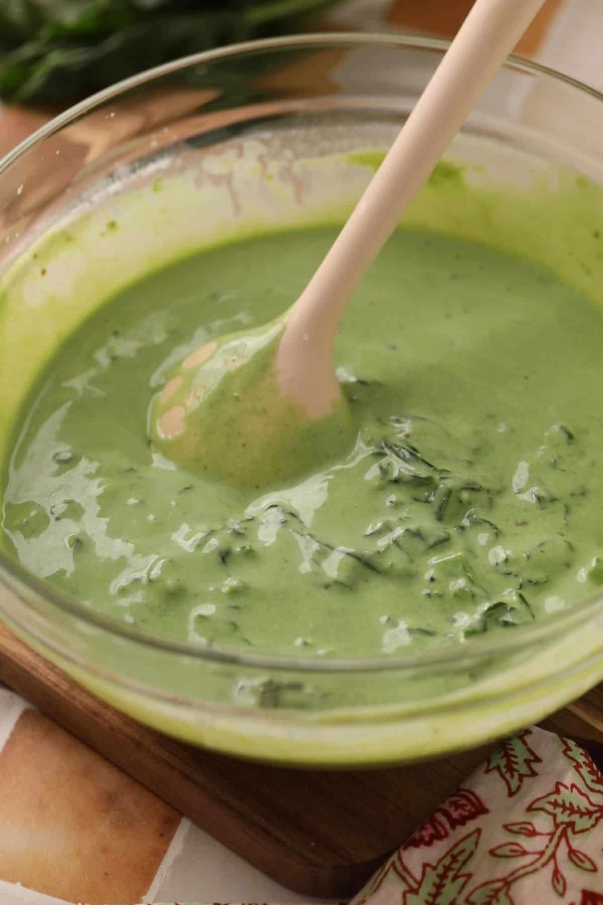 Sauteed spinach is added to green spinach yogurt and mixed to make raita.