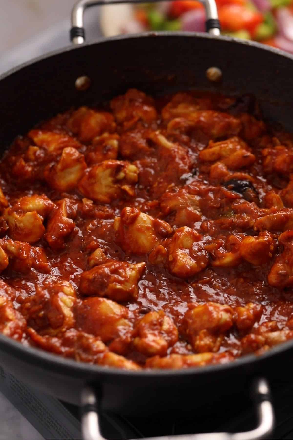 Chicken is mixed and fried with tomatoes.