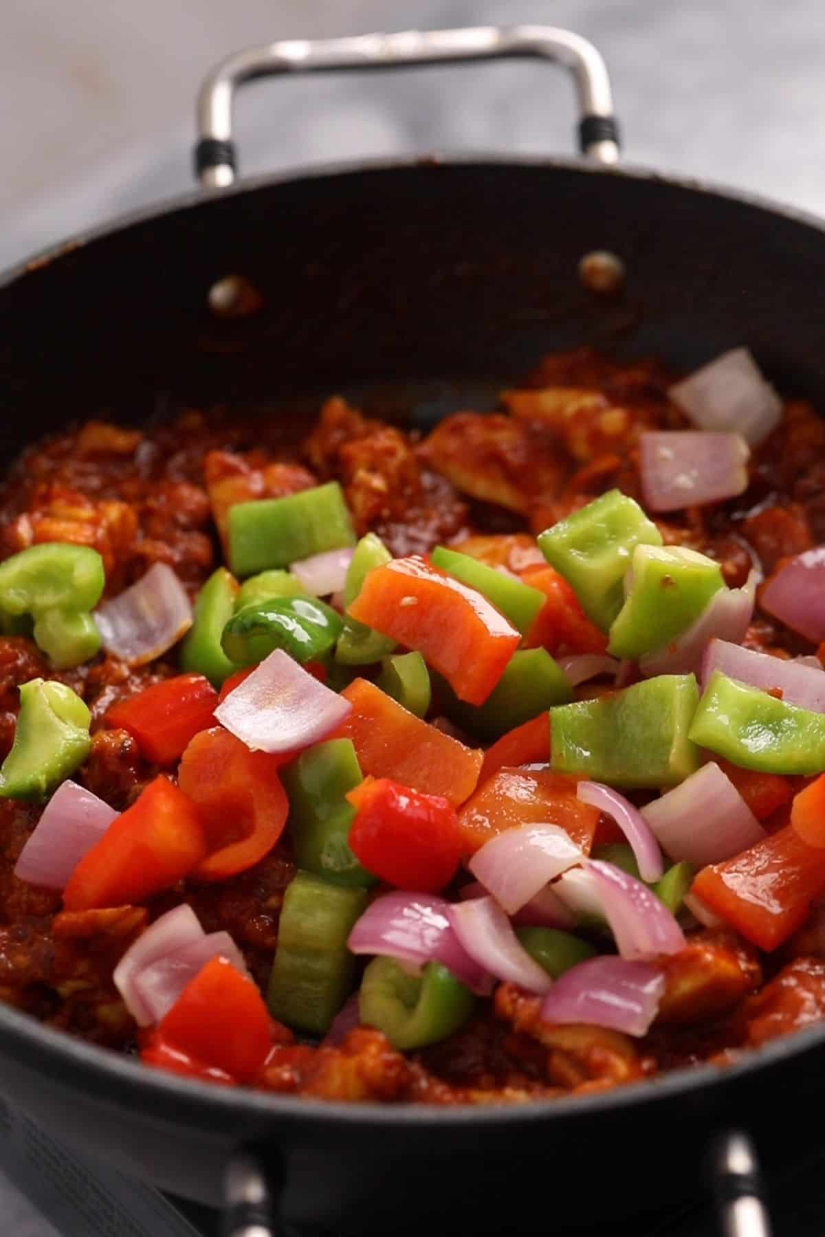 Bell peppers and onions are added to the jalfrezi.