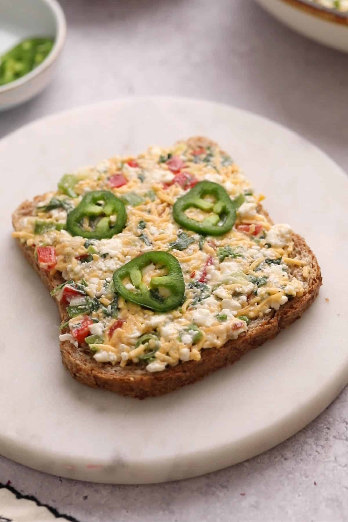 15-Minute Cottage Cheese Chilli Toast 11 Cheese mixture is spread on top of wheat bread slice.
