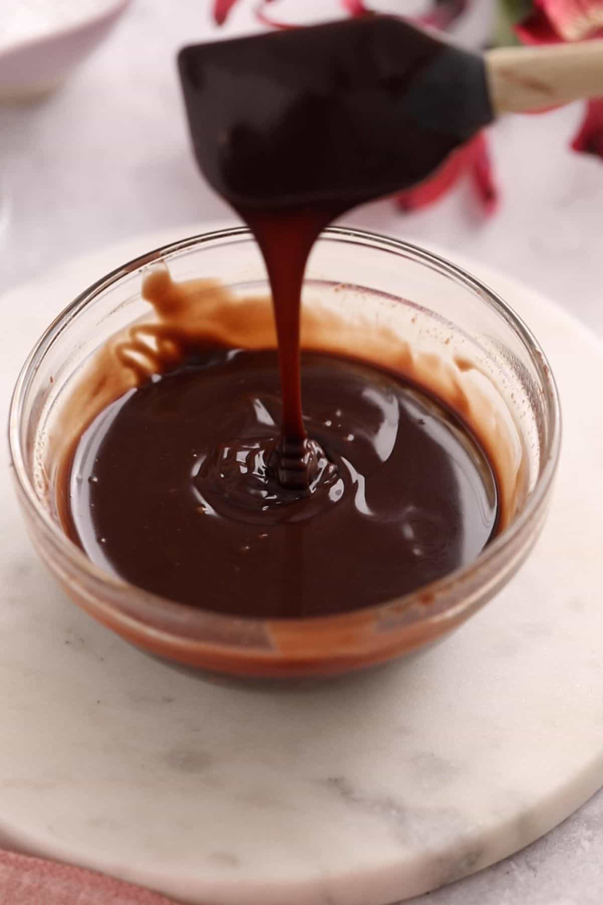 Smooth melted chocolate in a small glass bowl.