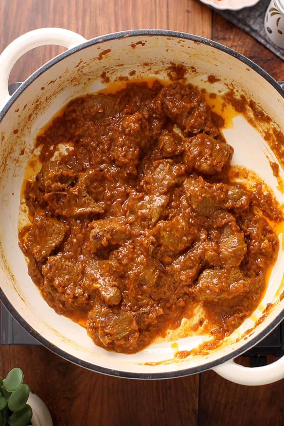 Restaurant-Style Lamb Korma (Rich & Creamy) 22 Lamb is cooking with onion tomato masala in a white pot.