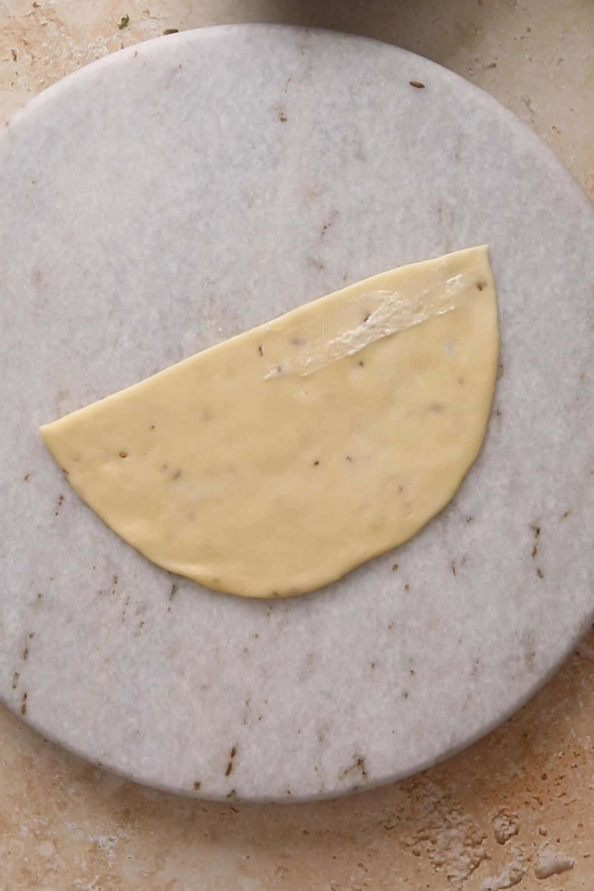 Classic Punjabi Samosa Recipe (Crispy & Flaky) 19 Flour slurry is spread on the straight edge of one semi circle.