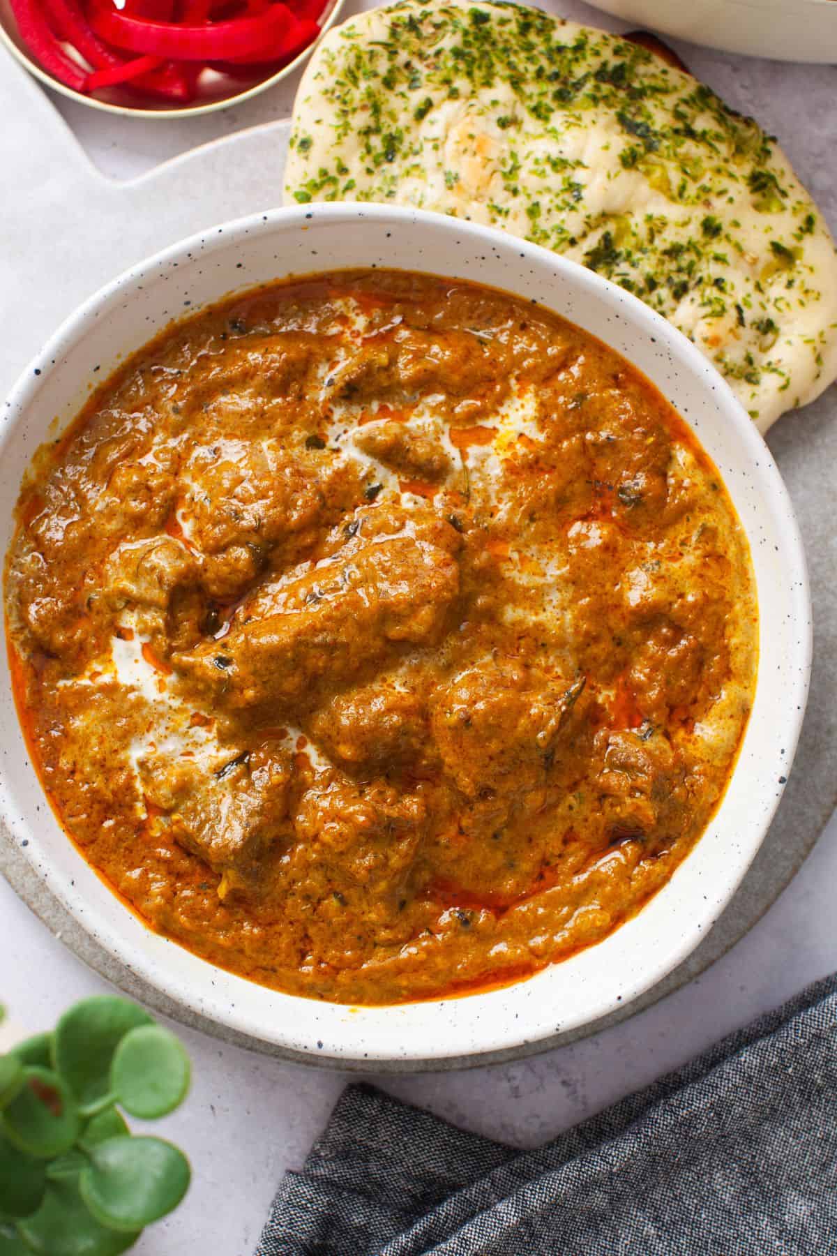 Restaurant-Style Lamb Korma (Rich & Creamy) 2 Creamy lamb korma served in a white dish with naan and pickled onions.