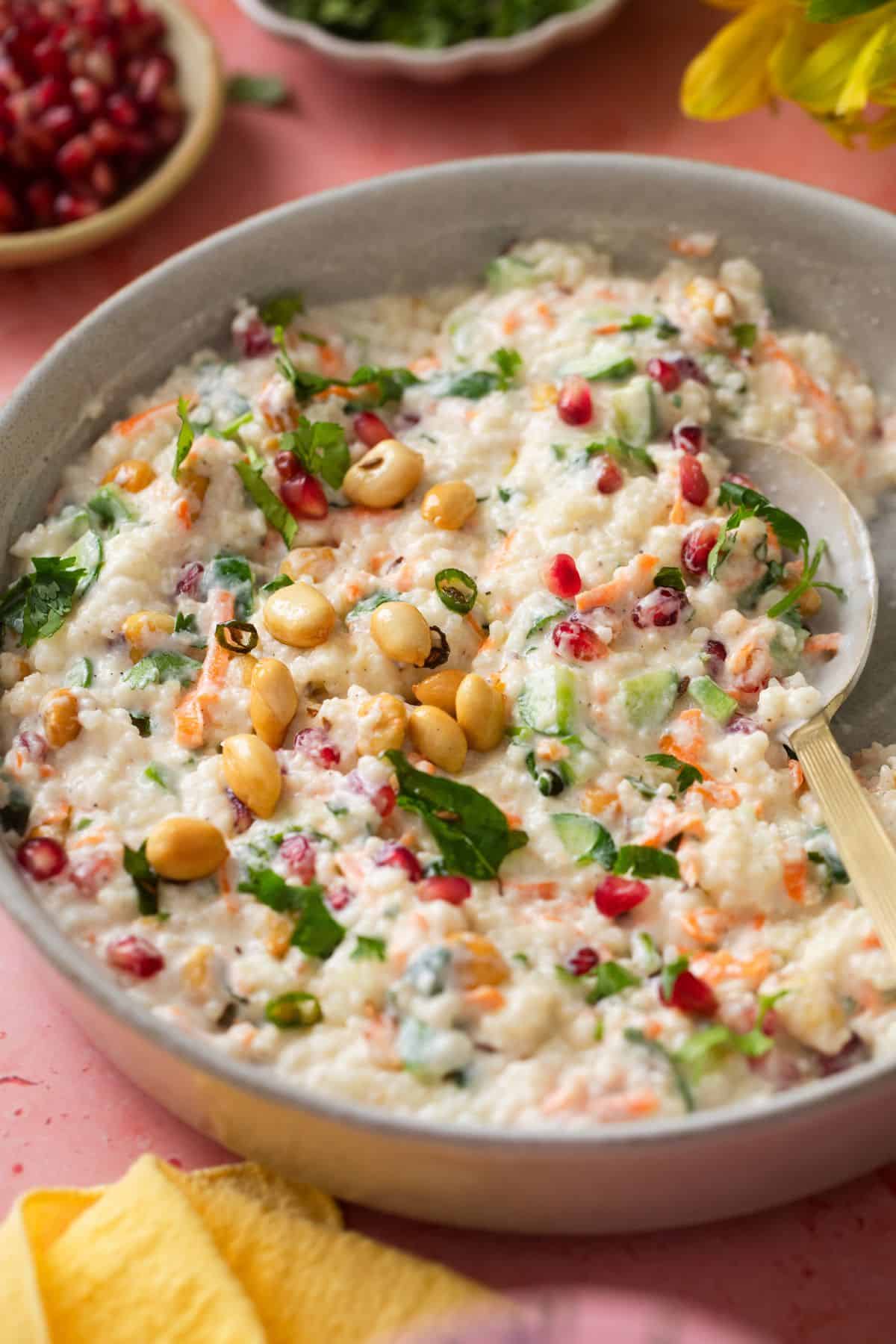 Curd Rice With Millets (Fasting Friendly) 3 Millets Curd Rice served in a white stone shallow plate with a golden spoon.