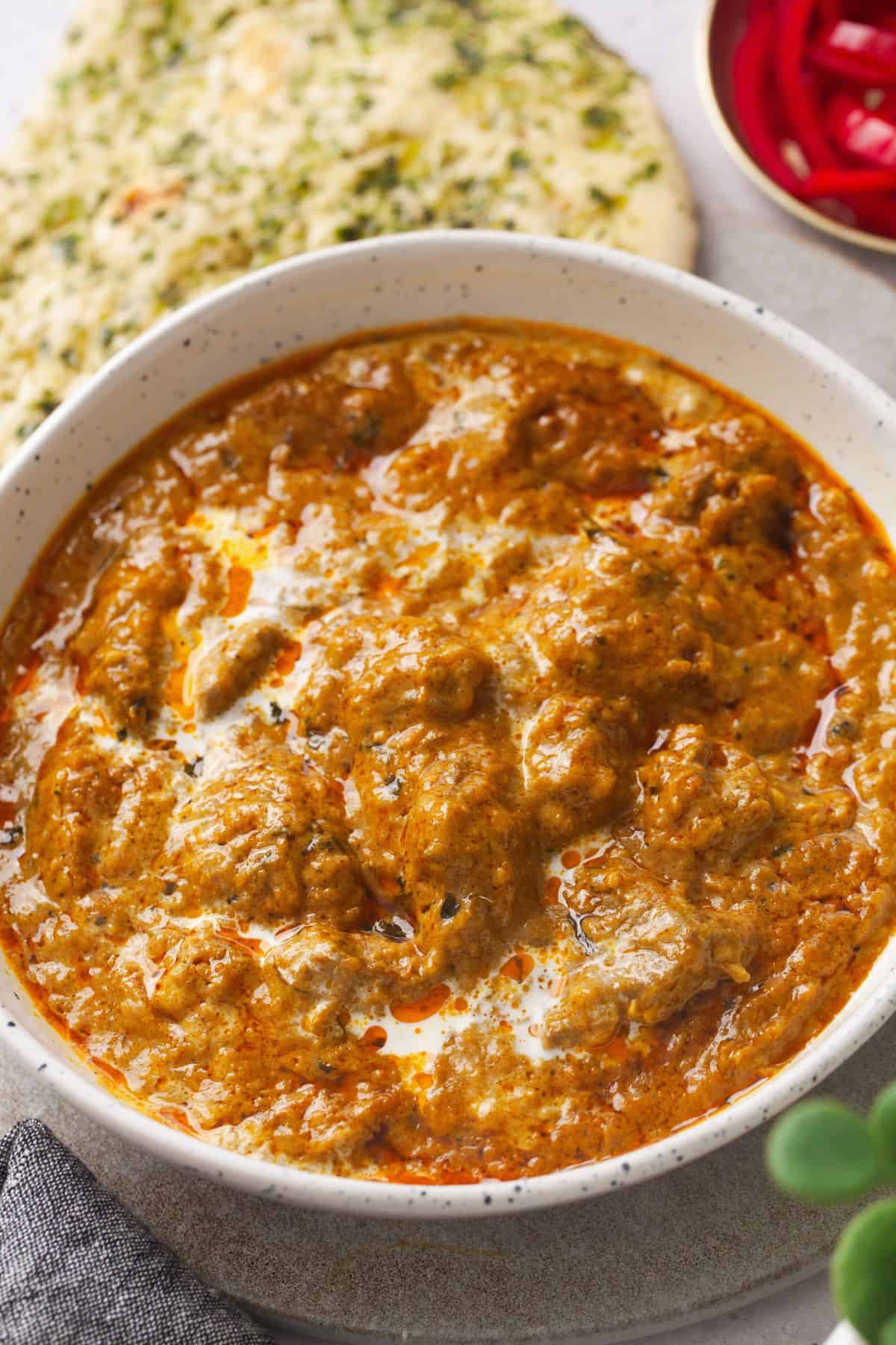 Restaurant-Style Lamb Korma (Rich & Creamy) 6 An angled view of lamb kprma curry with naan in background.