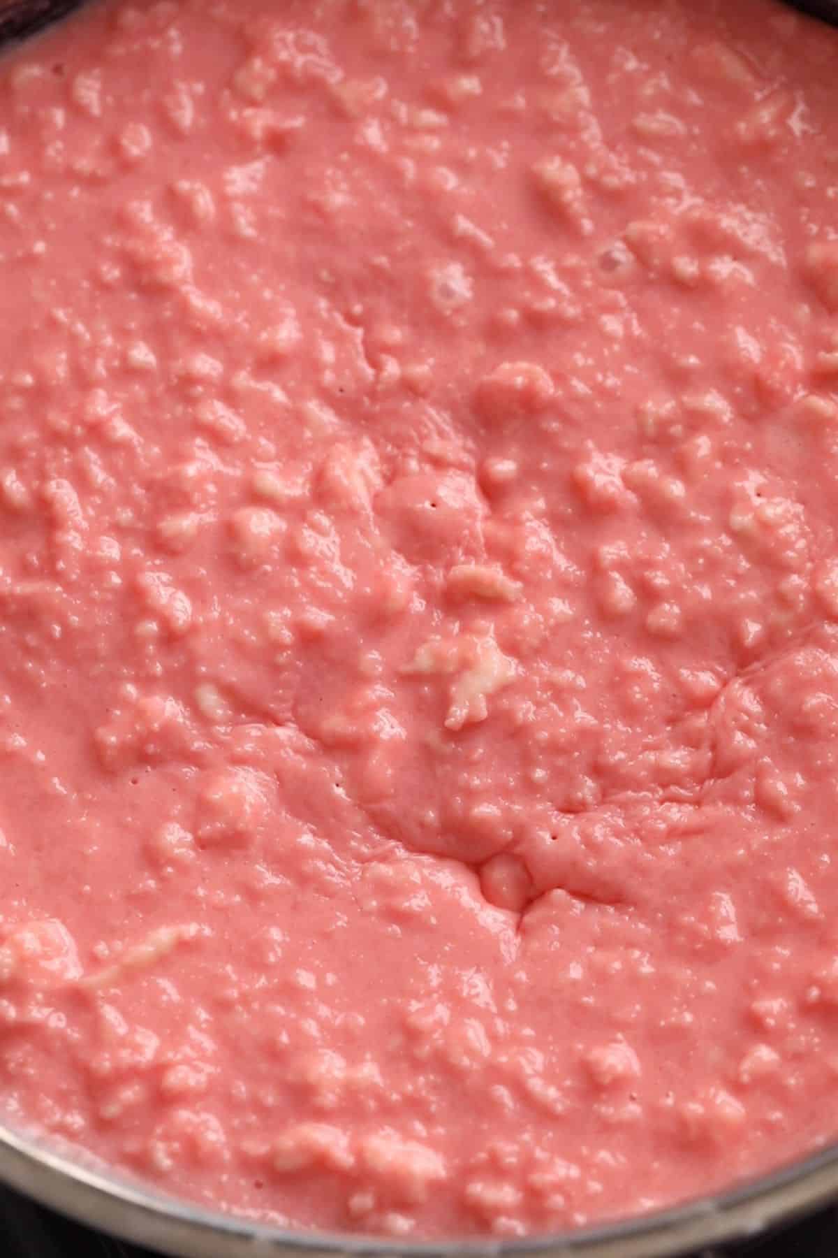 Rose Kalakand Recipe (With Paneer) 11 Paneer and rose milk mixture is slow cooking in a black pan.