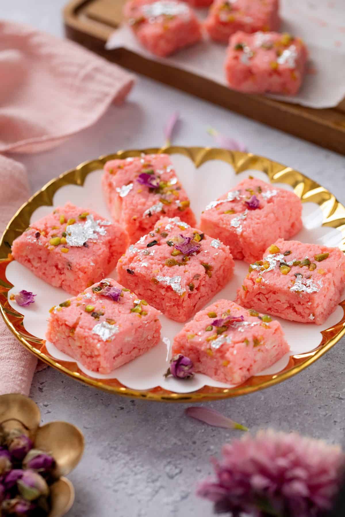 Rose Kalakand Recipe (With Paneer) 2 Rose kalakand is placed in a white and gold plate with a pink cloth in background.