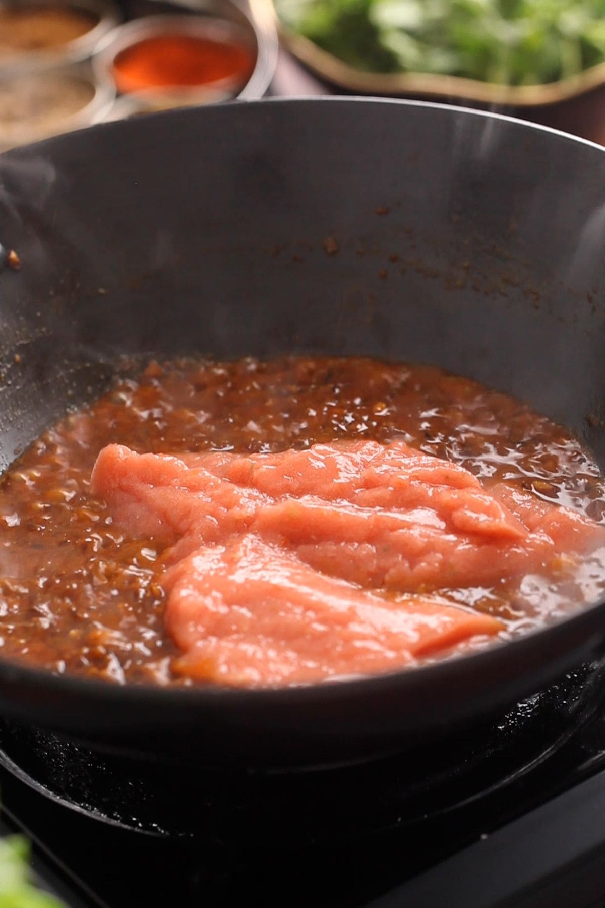 Blended tomatoes are added to the masala. 