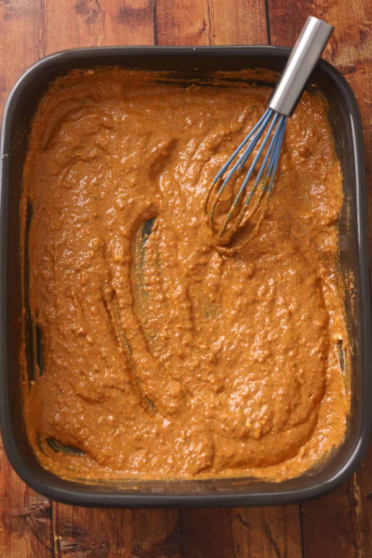 Yogurt marinade for lamb is whisked and is orange in color.