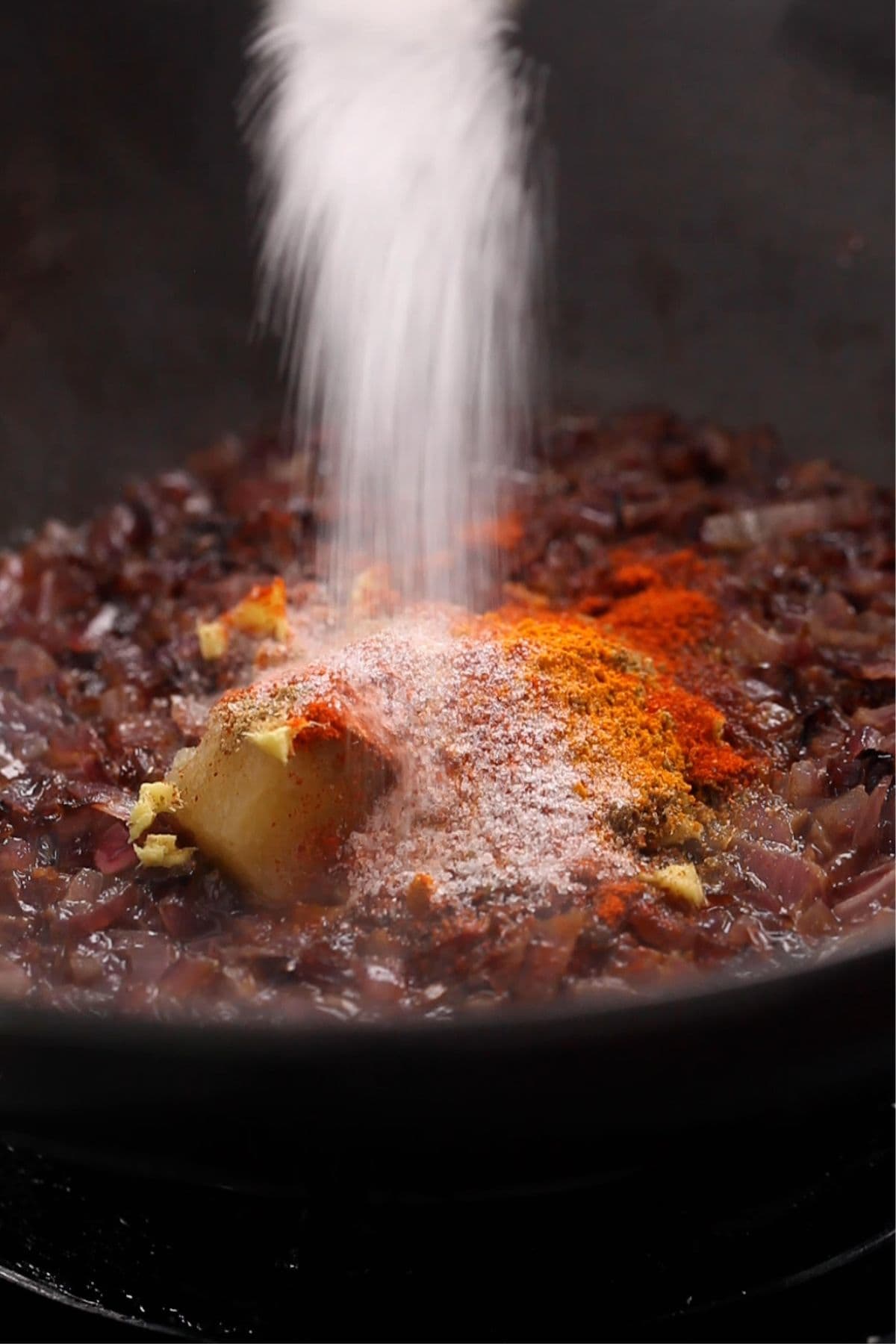 Spices are added along with ginger and garlic to the browned onions.