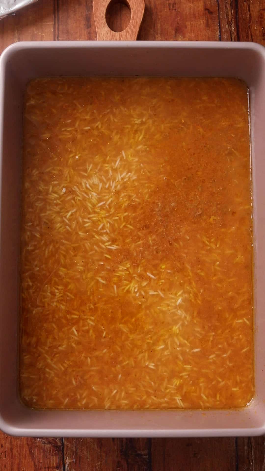 Baking dish filled with uncooked rice broth or is ready to be baked.