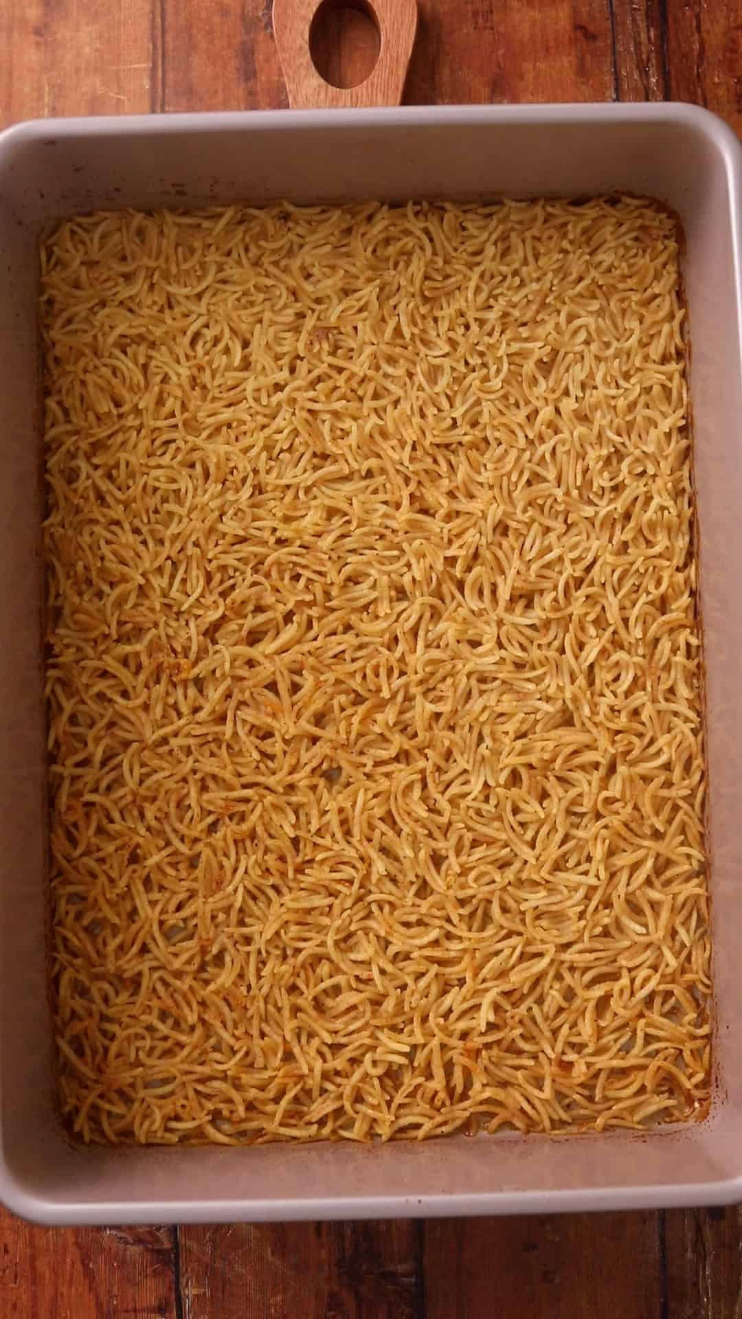 Baking pan is filled with a layer of baked, fluffy cooked basmati rice that cover the entire surface.