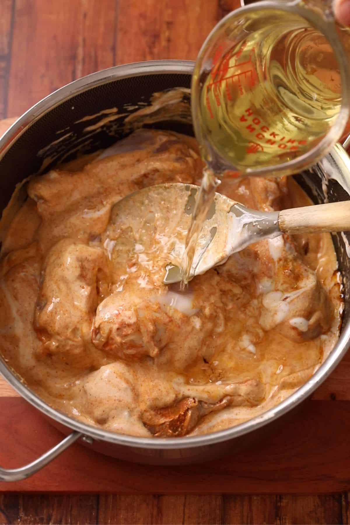 Adding yogurt and oil to the chicken pieces.