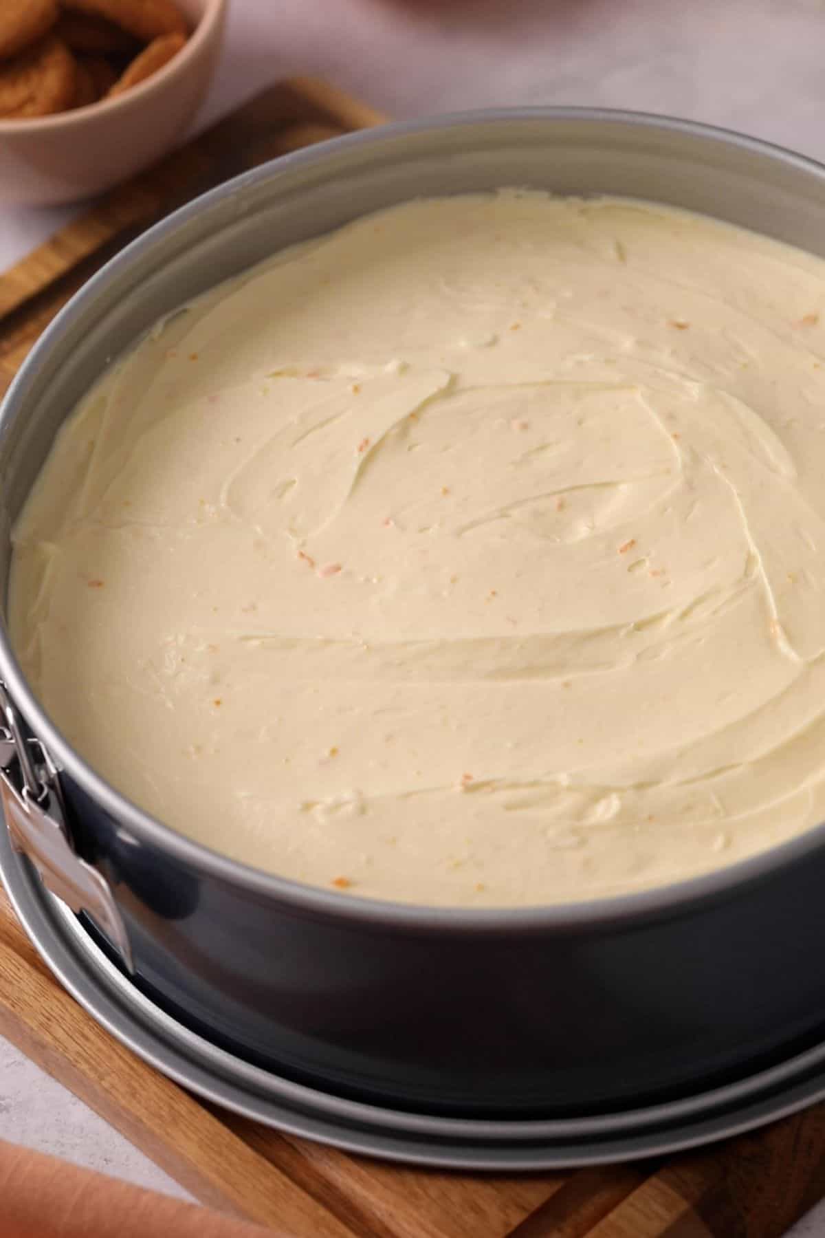 Cheesecake filling is added over the crust in a spring form pan.