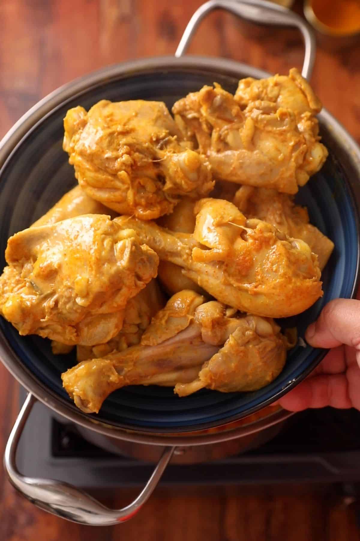 Chicken pieces are taken out in a blue plate. 