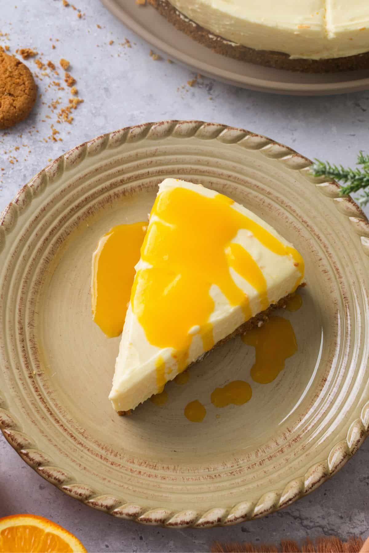 Closeup of a slice of orange cheesecake drizzled with orange sauce.