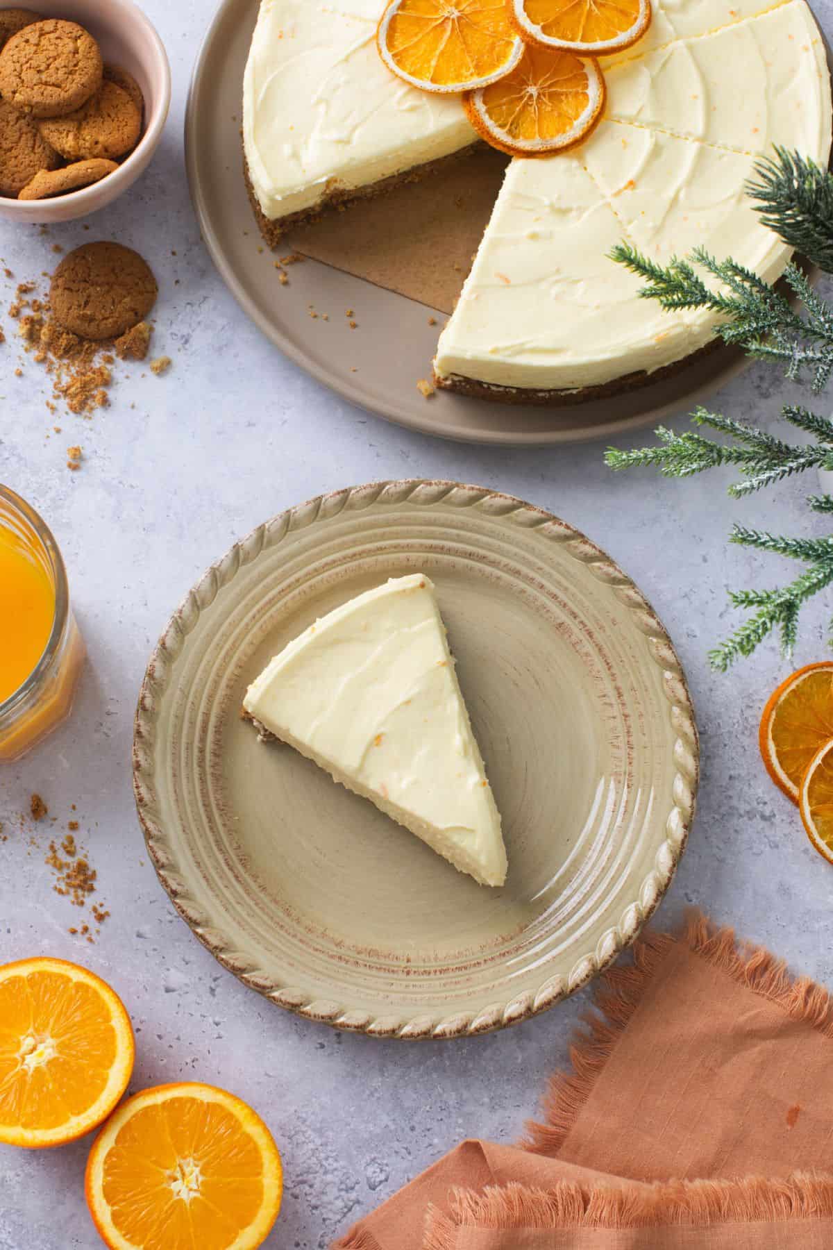 A neatly sliced orange cheesecake sliced is placed on a beige plate with orange sauce on the side. we can also see ginger snaps and rest of cheesecake in the image.