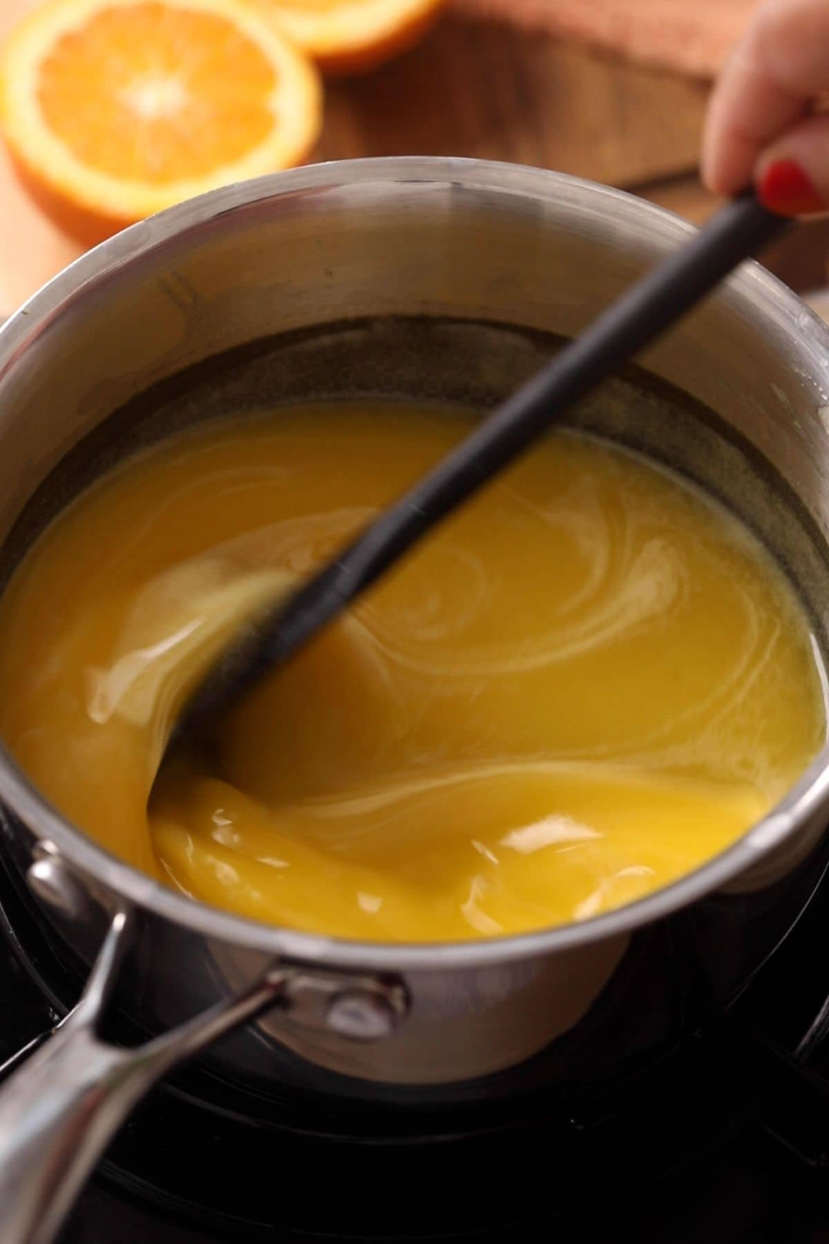 Making orange curd in a small black sauce pan.