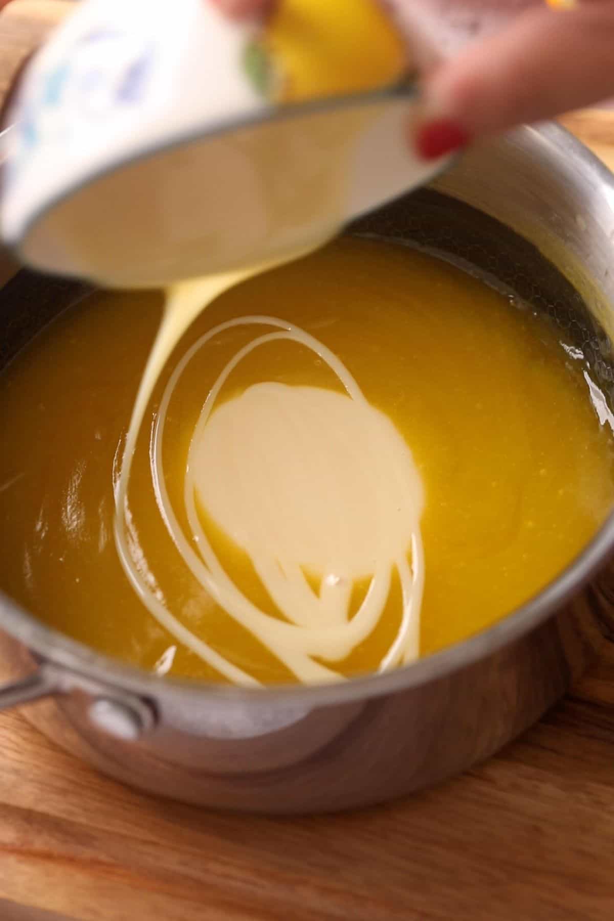 Condensed milk is being added to the orange curd.