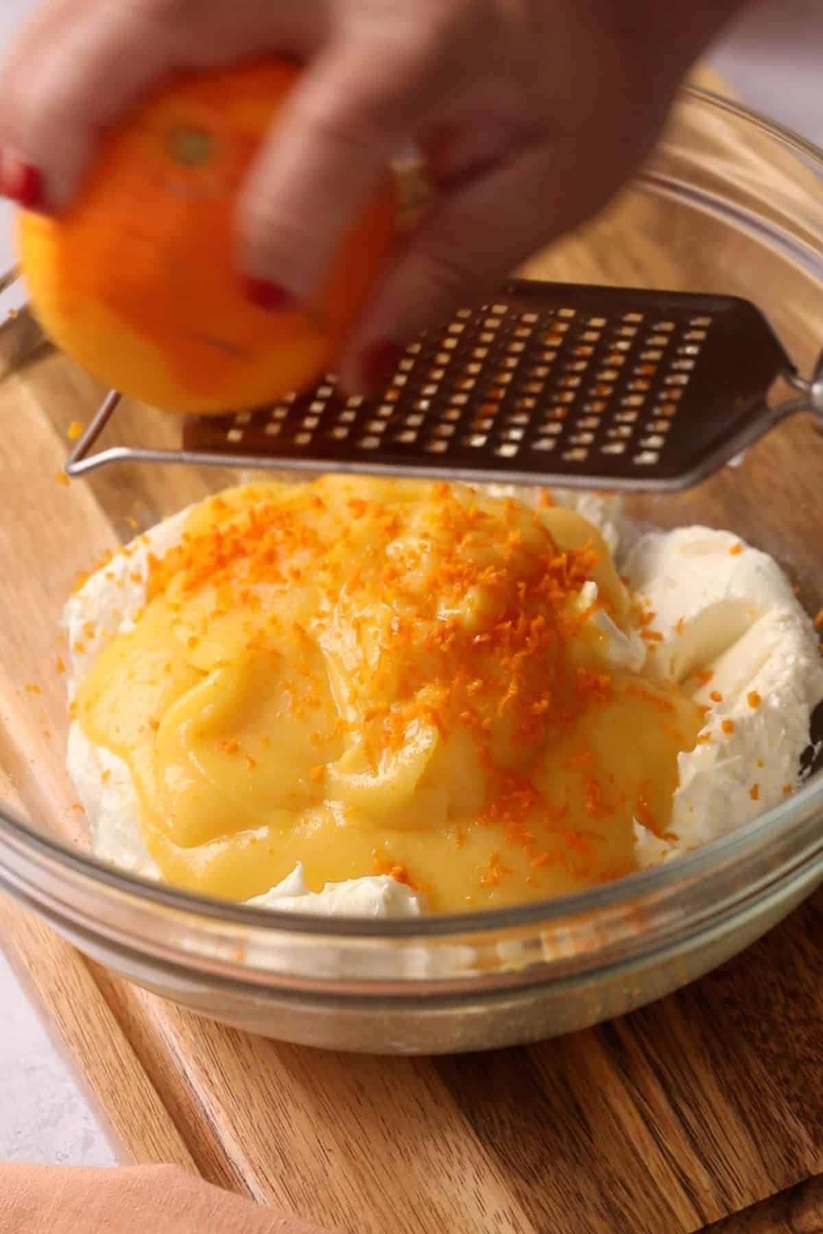 Orange zest is being grated over the cheese filling.