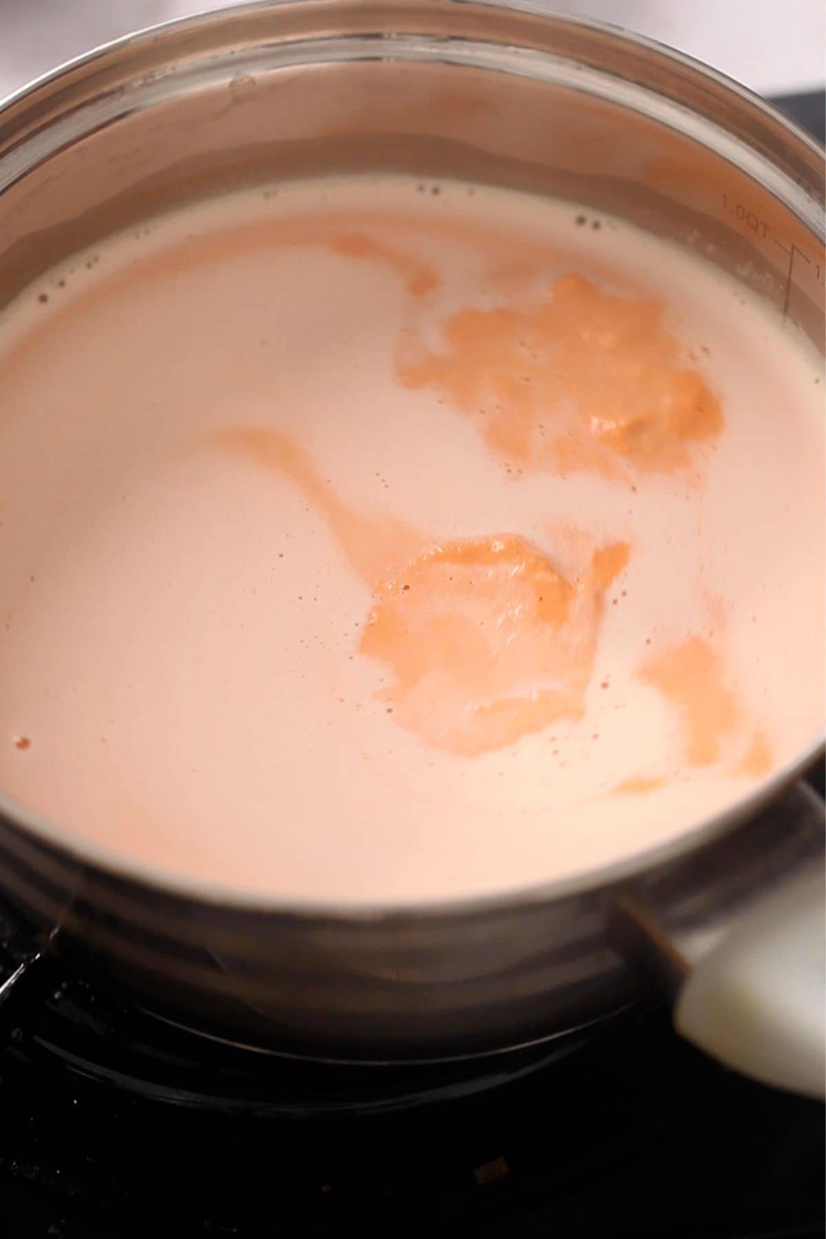 Carrot paste and milk are mixed in a small steel pot.