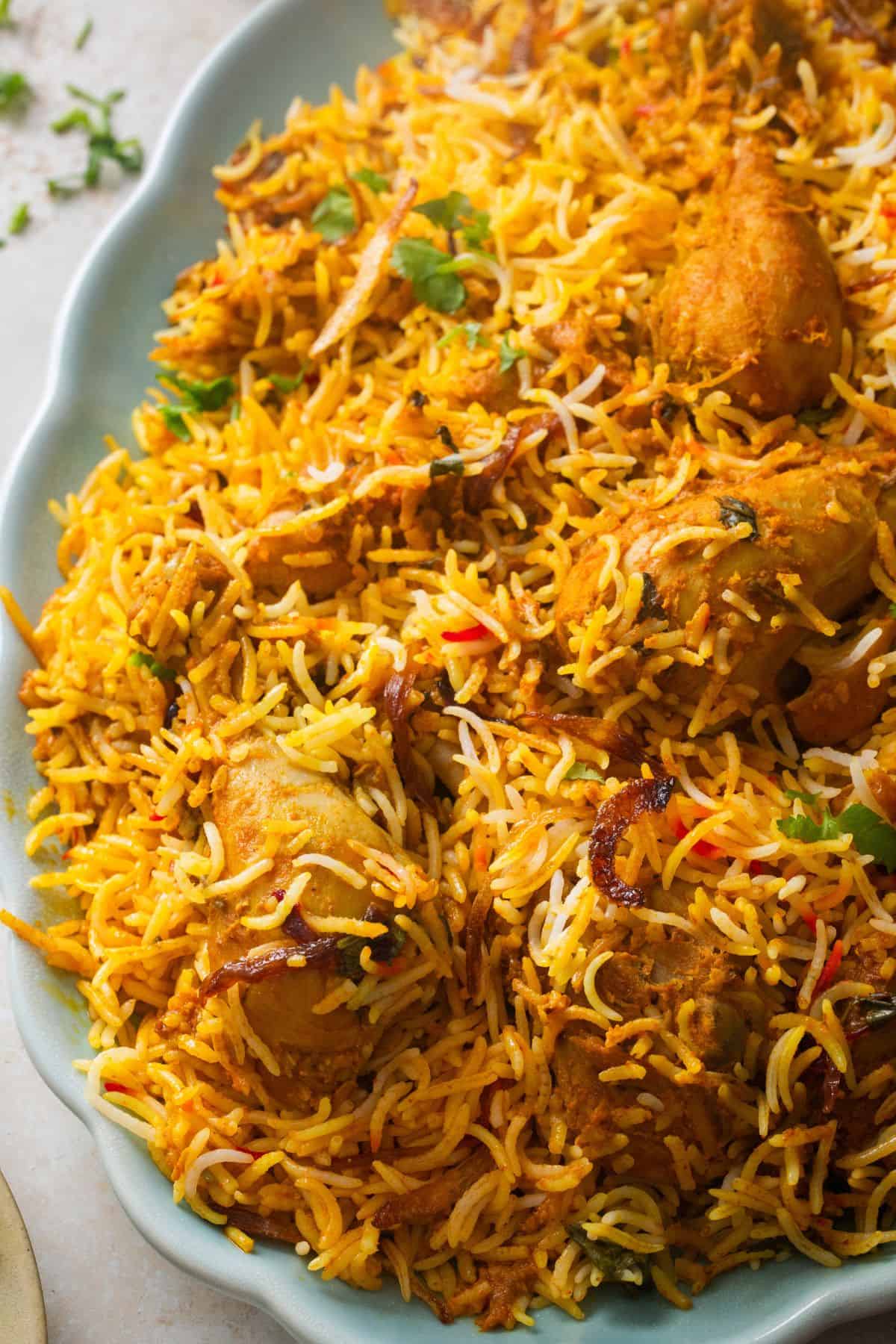A macro shot of dum chicken biryani served in a light blue platter.