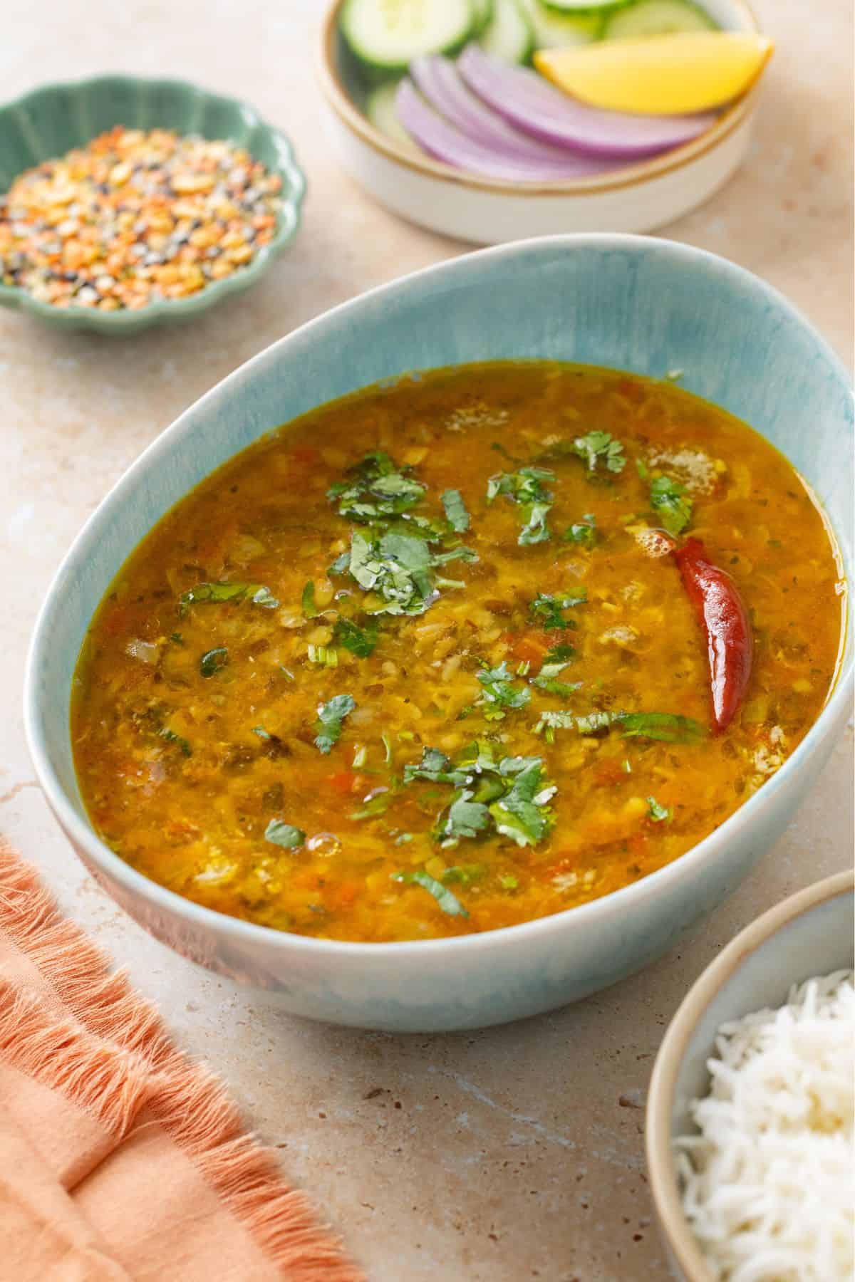 Side image of mixed dal with rice and raw lentils in background.