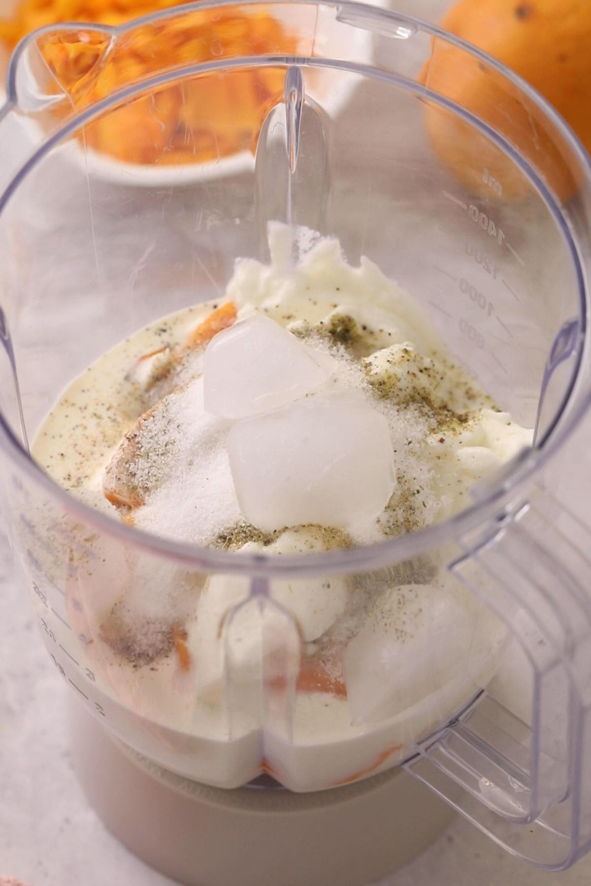 Mango, yogurt, ice cubes and all ingredients are placed in a blender jar.