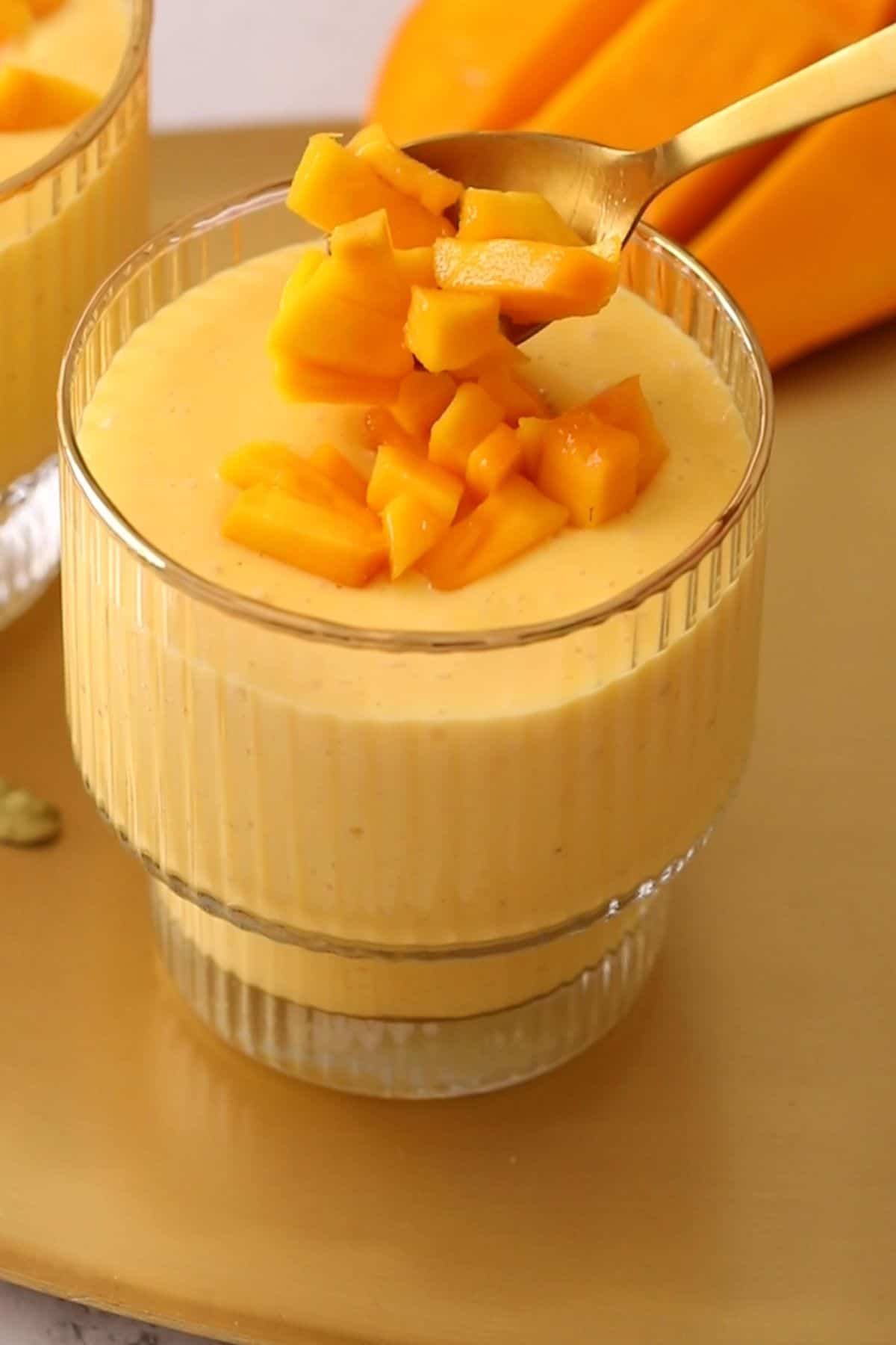 Lassi is being topped with finely chopped mango.