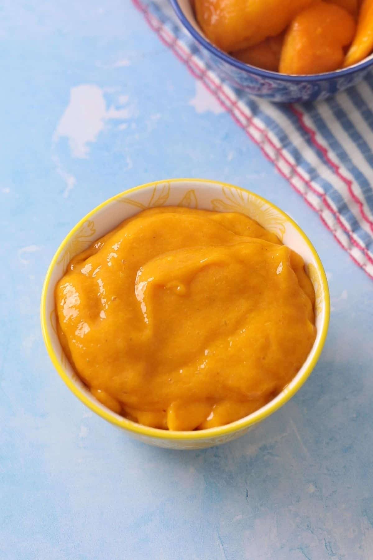 Smooth mango pulp in a yellow bowl.