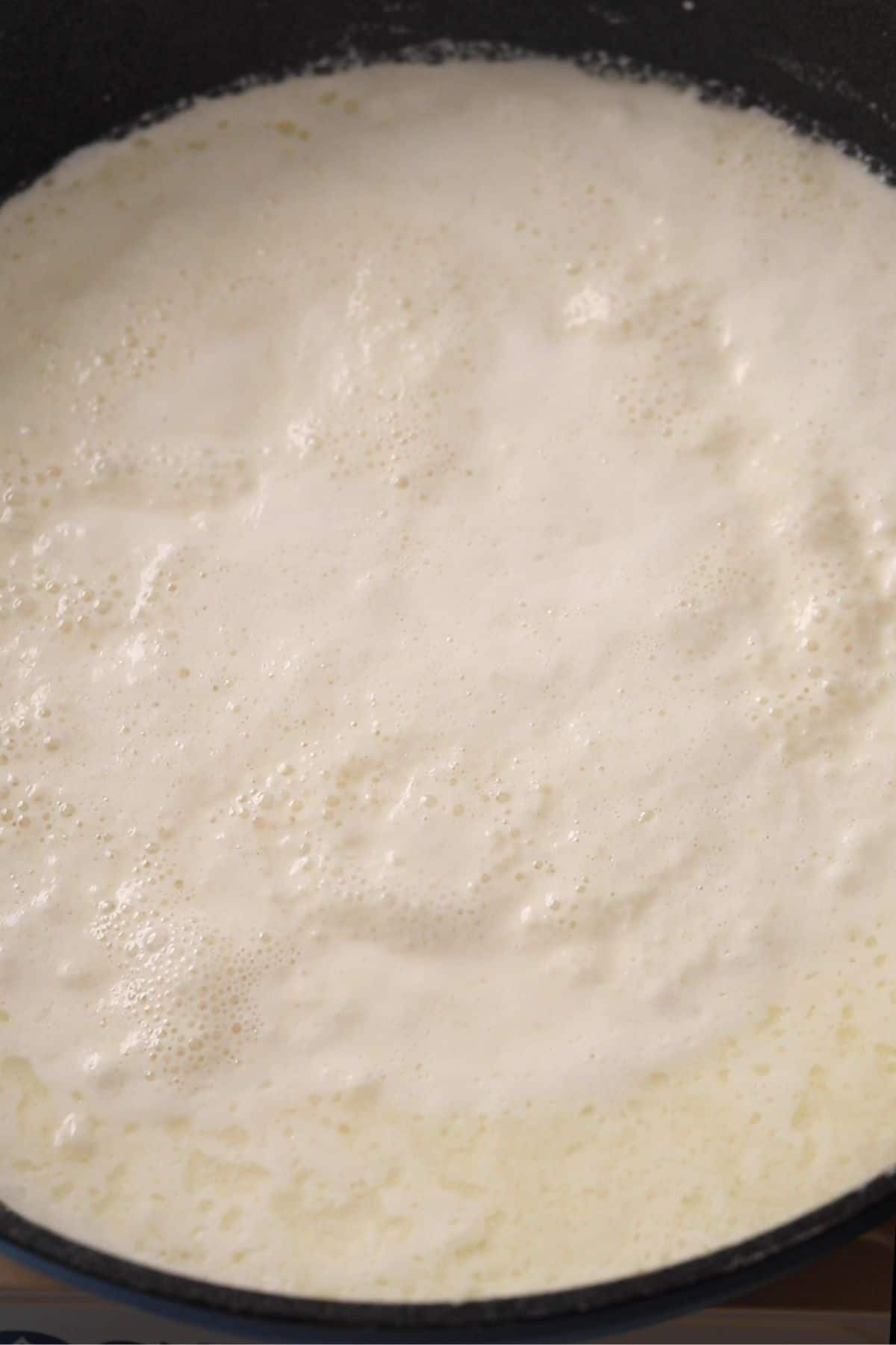 Milk mixture has thickened and reduced in volume.