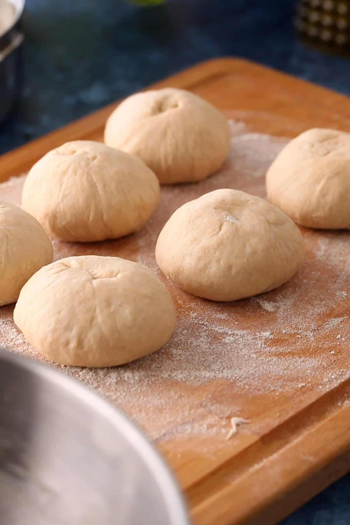 Atta dough balls are placed on a floured surface for making naan.