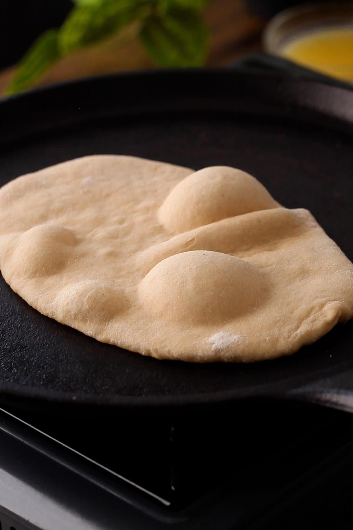 Puffy atta naan on a cast iron griddle.
