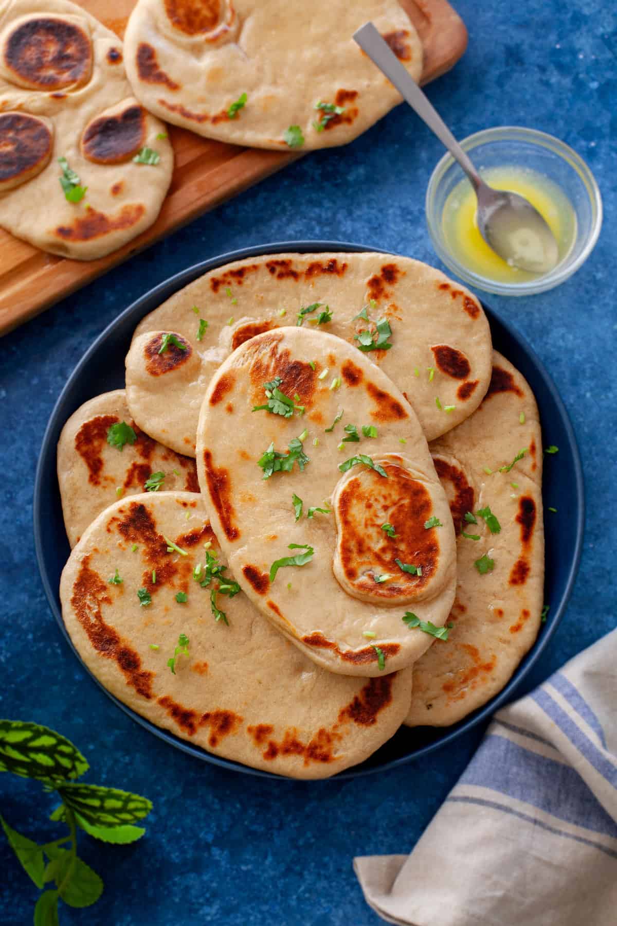 Atta Naan are placed in a black platter with a small bowl of butter on the side.
