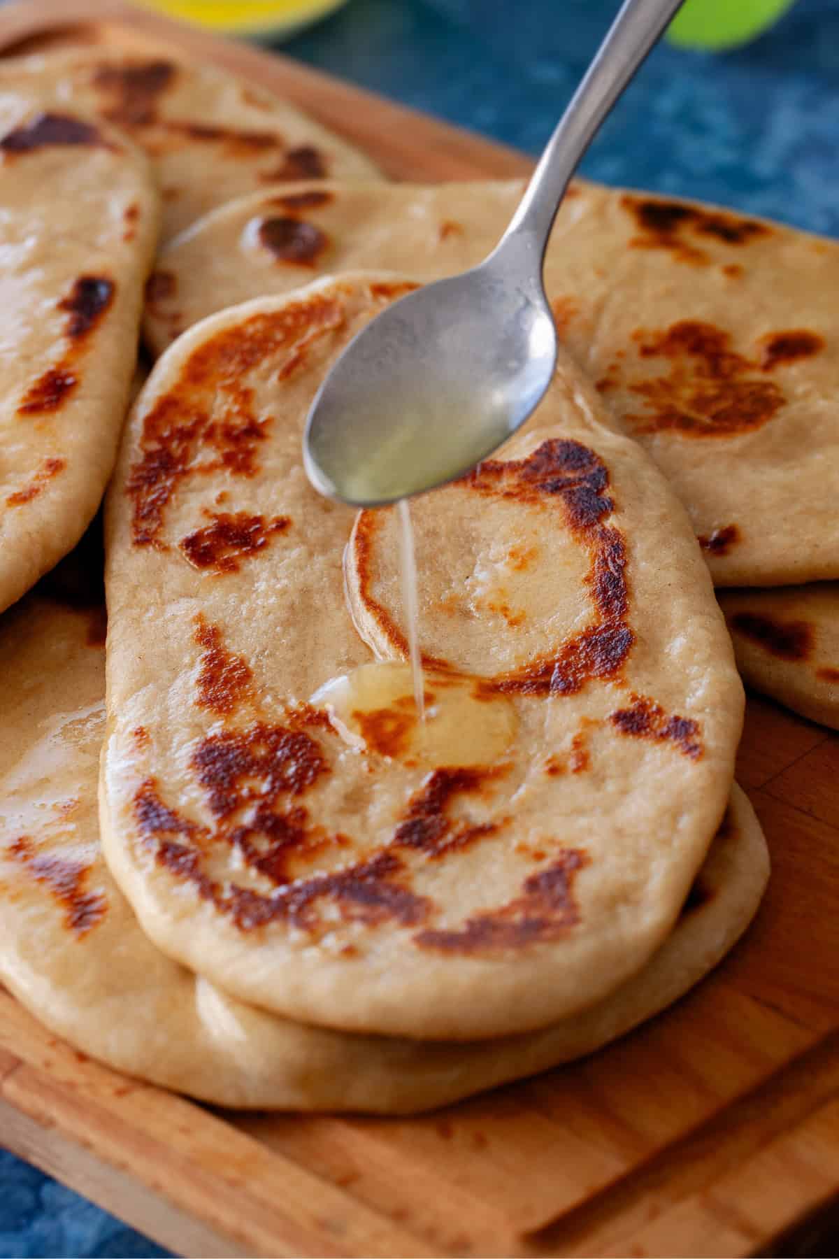Ghee is being drizzled on whole wheat naan.