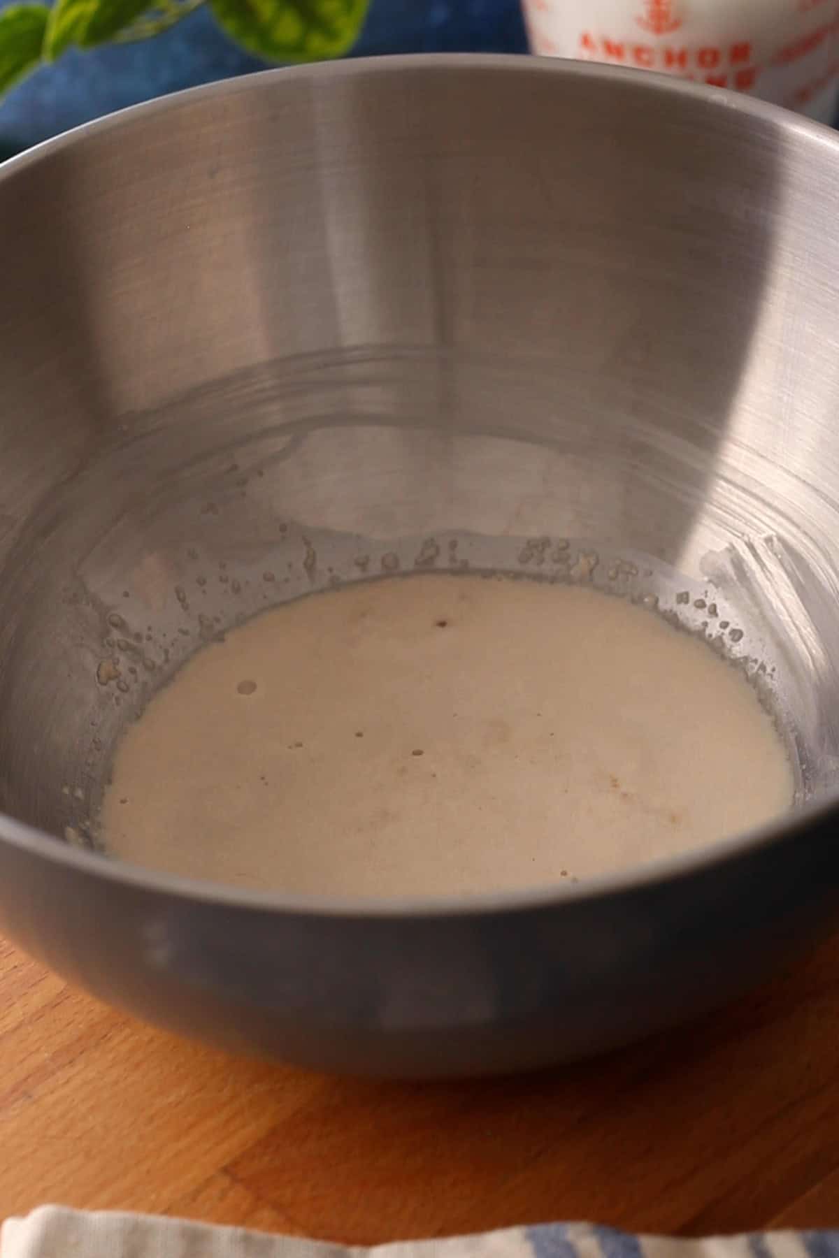 The bloomed yeast mixture in a large steel mixing bowl.