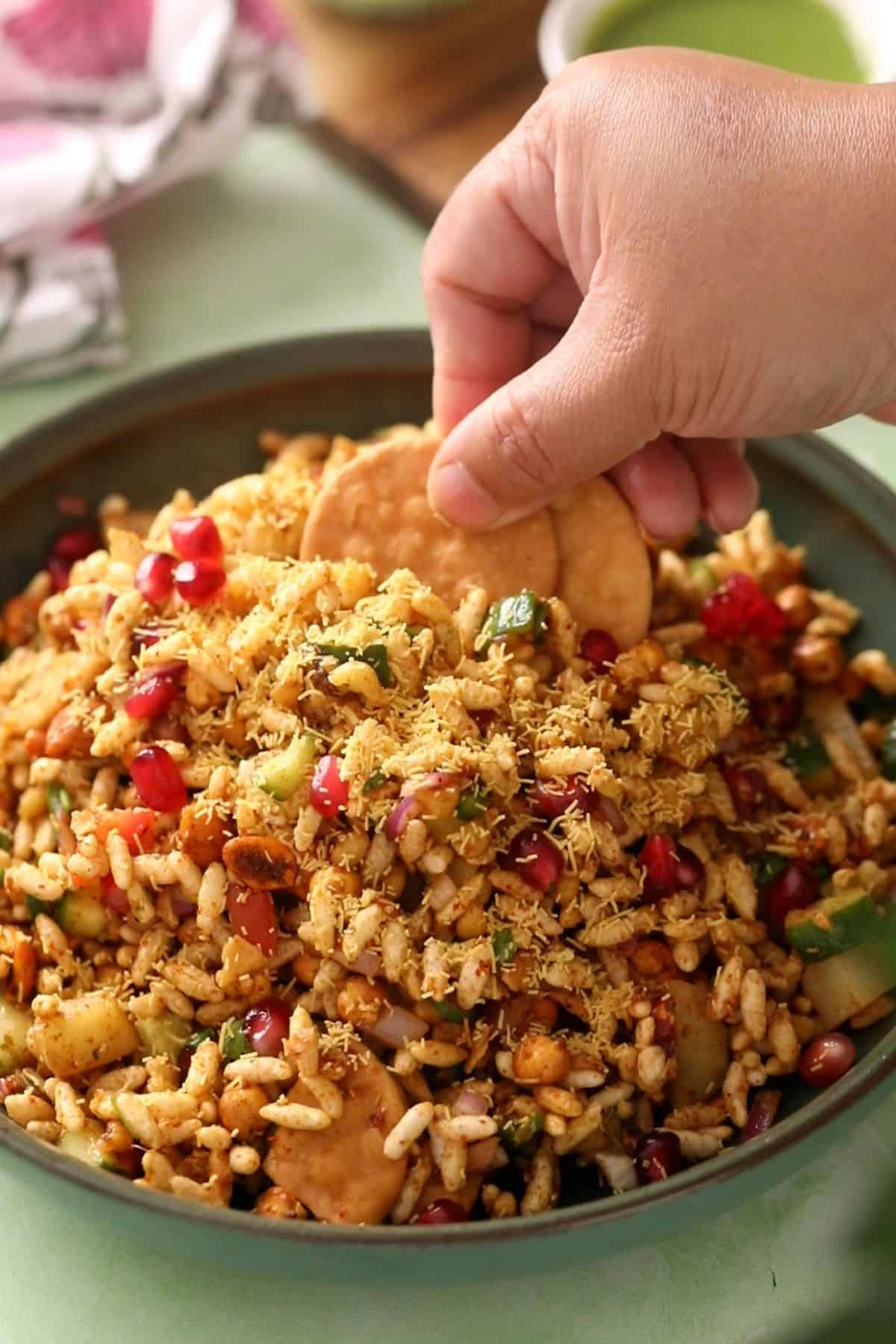 Bhel puri is served and papri are added to it.