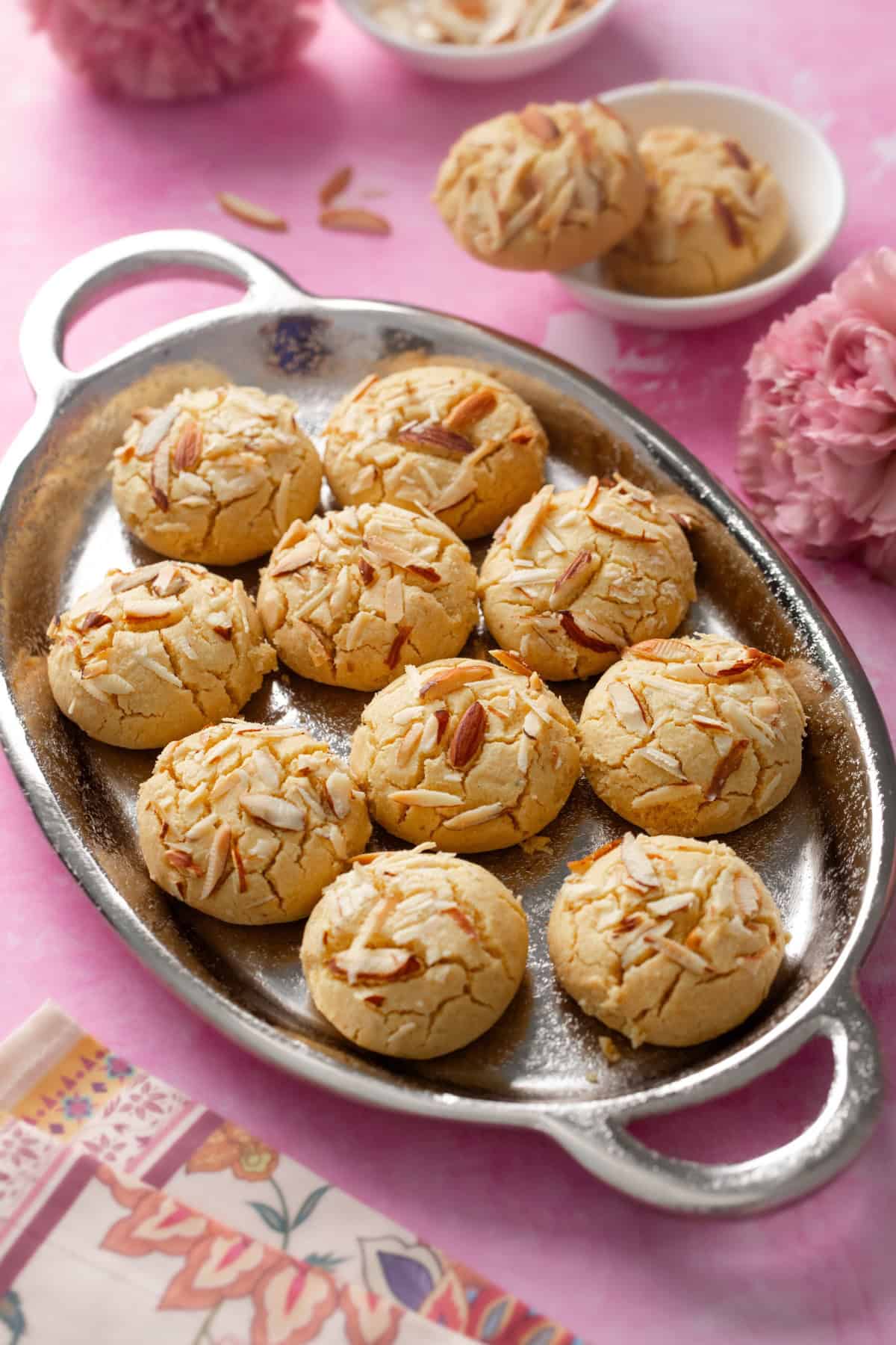 Angled view of besan nankhatai placed in a silver oval platter.