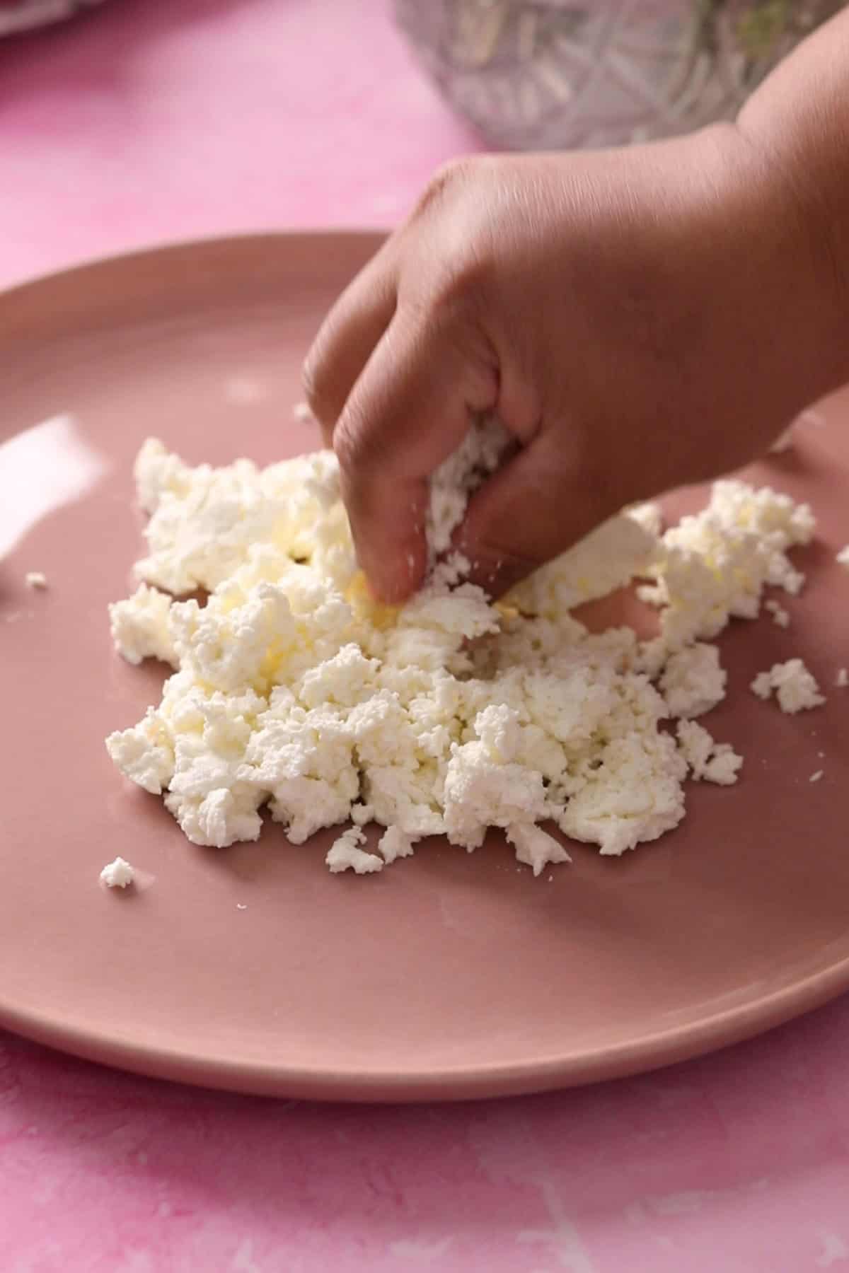 Crumbling chenna placed on a pink plate.